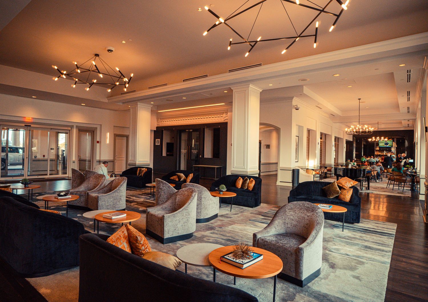 Modern open concept living room with track lighting, grey carpet, and contemporary furniture showcases panoramic city views.