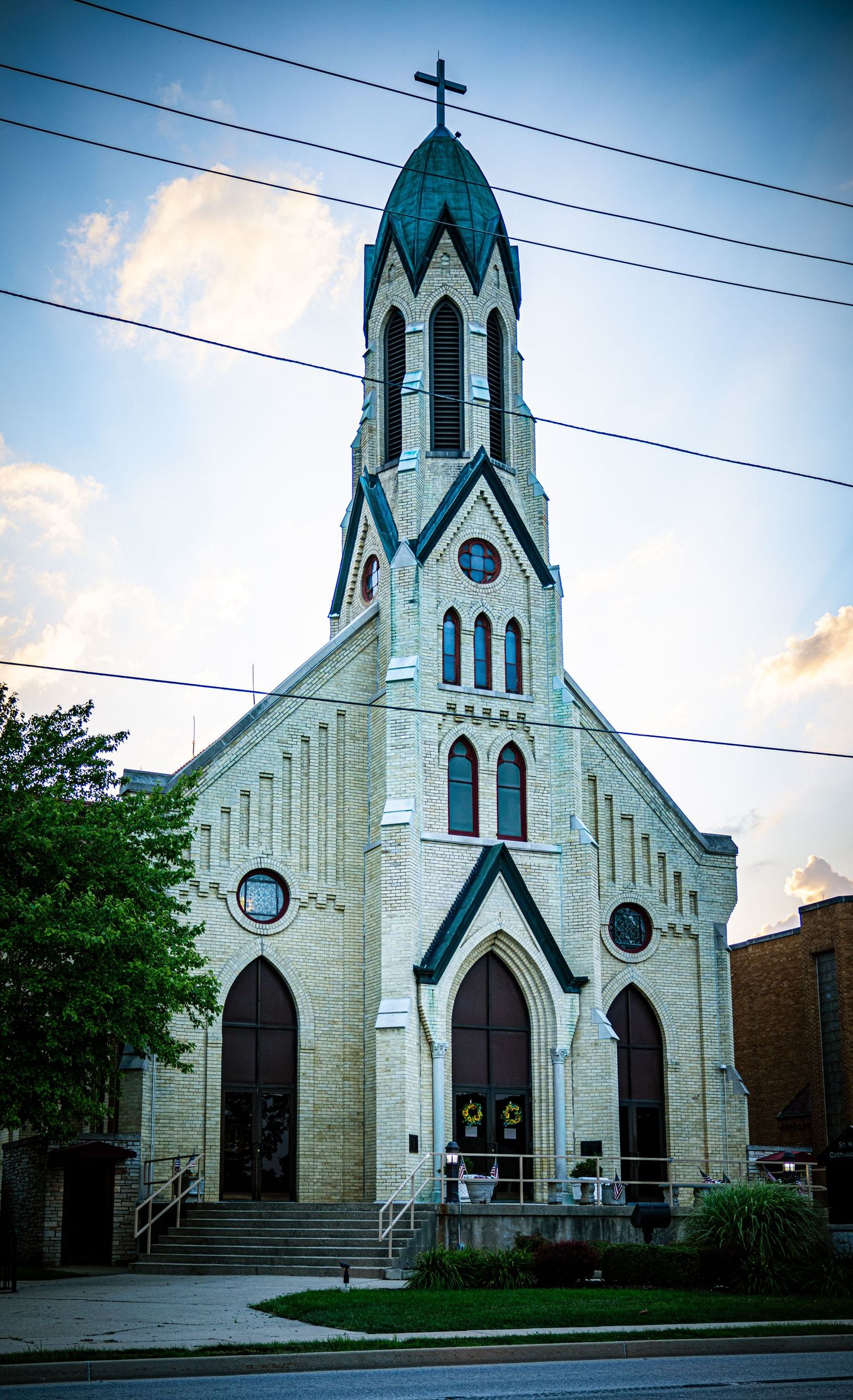 Gothic revival church with white stone walls and blue spires photographed at dusk.