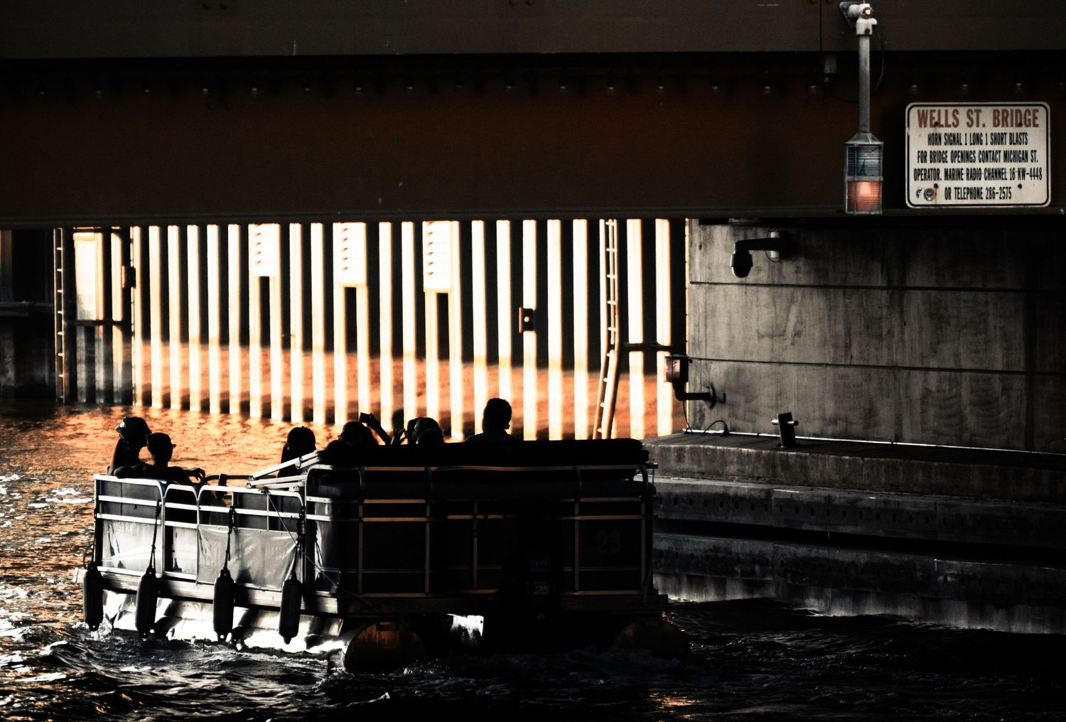 Silhouettes of people and boats against a bright sunset on the waterfront.
