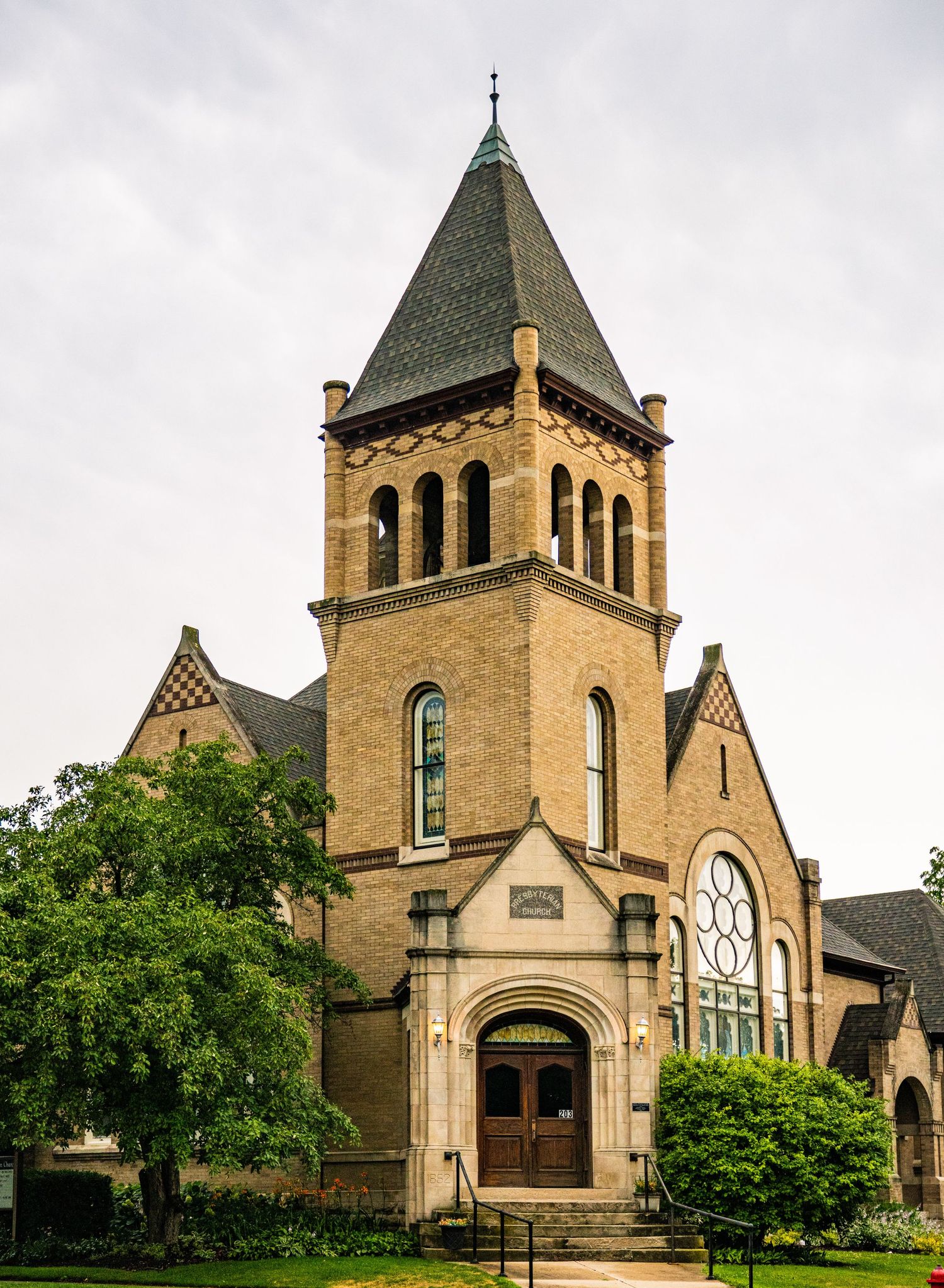 Historic yellow brick church building with multiple Gothic spires and arched windows in panoramic view.