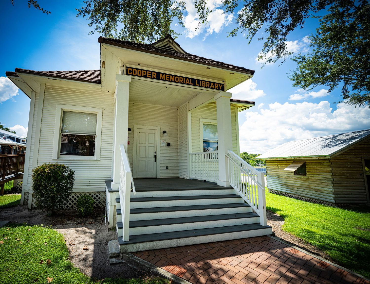 White historic building with front porch and steps on a sunny day.