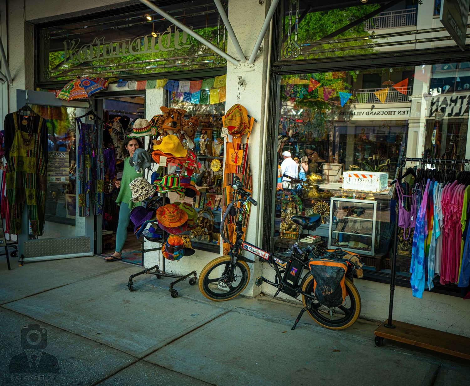 Colorful retail storefront displaying beach merchandise, clothing, and a parked bicycle on the sidewalk.
