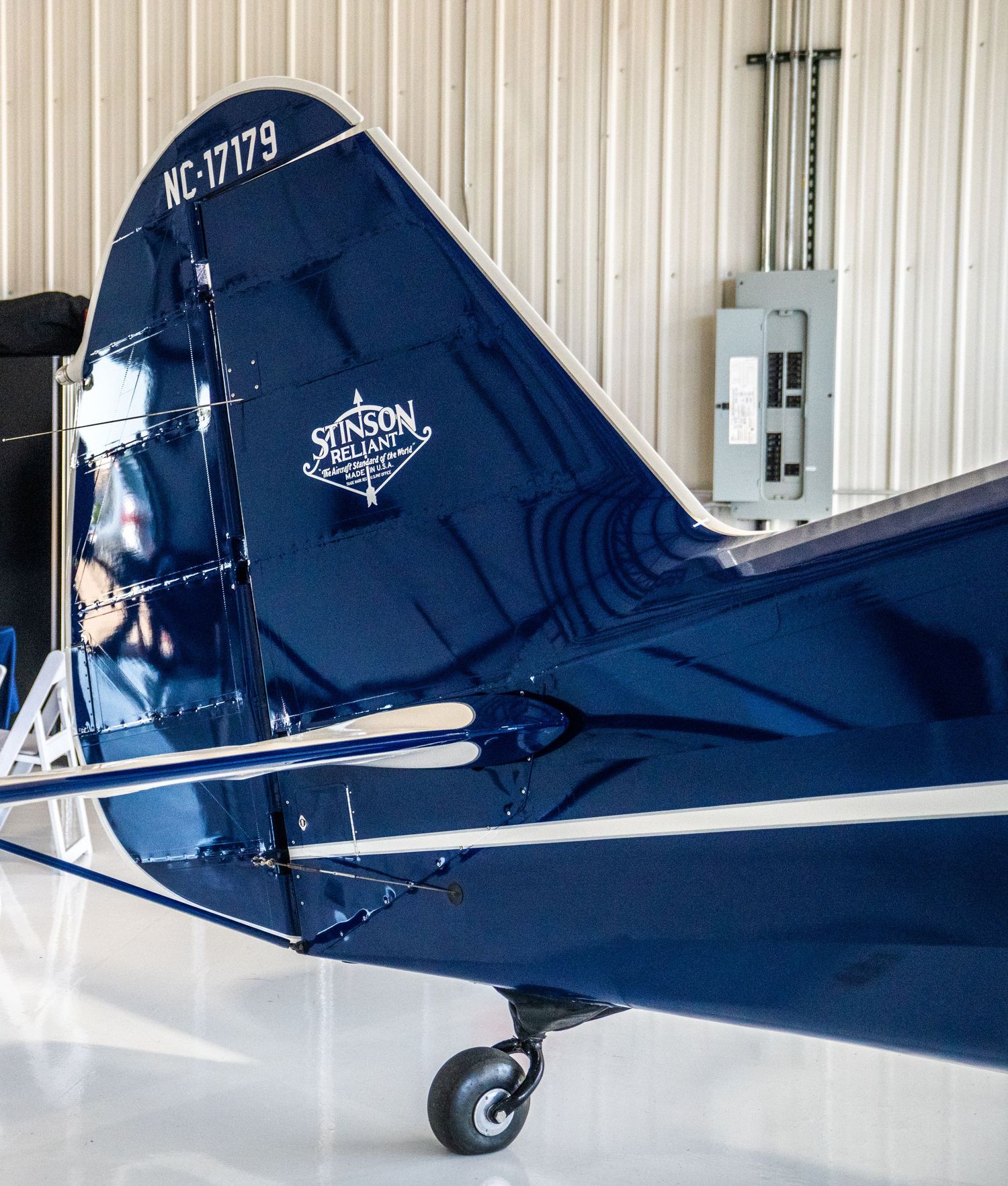 Close-up view of a navy blue aircraft tail section with white trim details parked in a hangar.