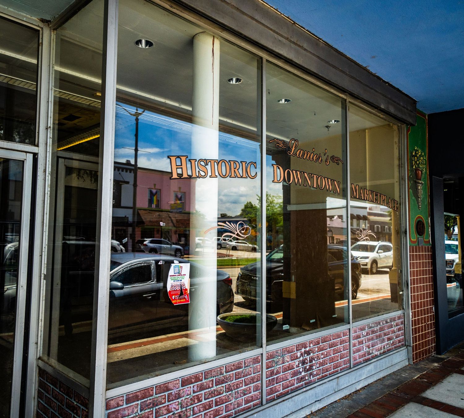Storefront window with retro-style lettering and signage reflecting nearby buildings.
