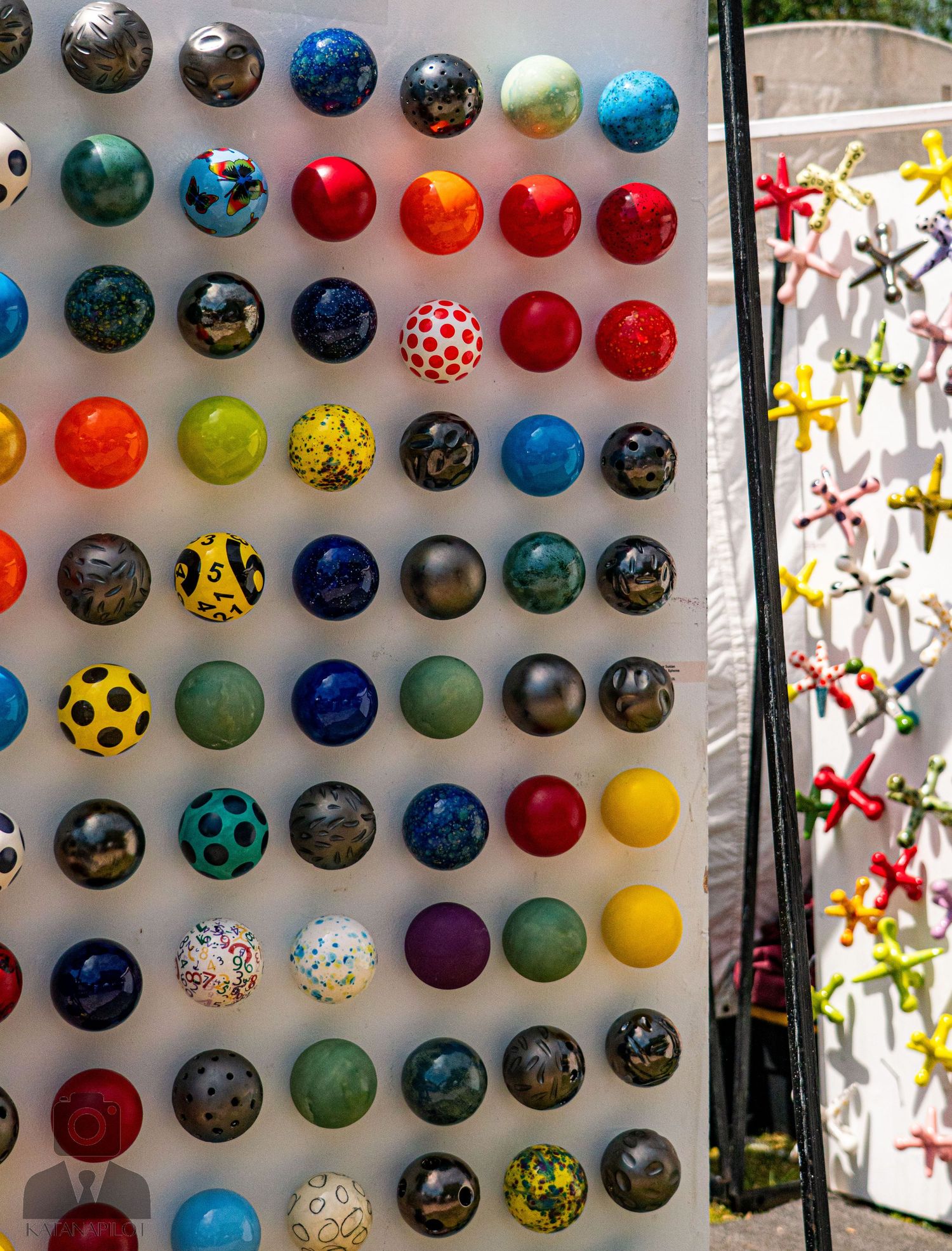 Collection of vibrant glass ornaments arranged in rows on a white wall display.