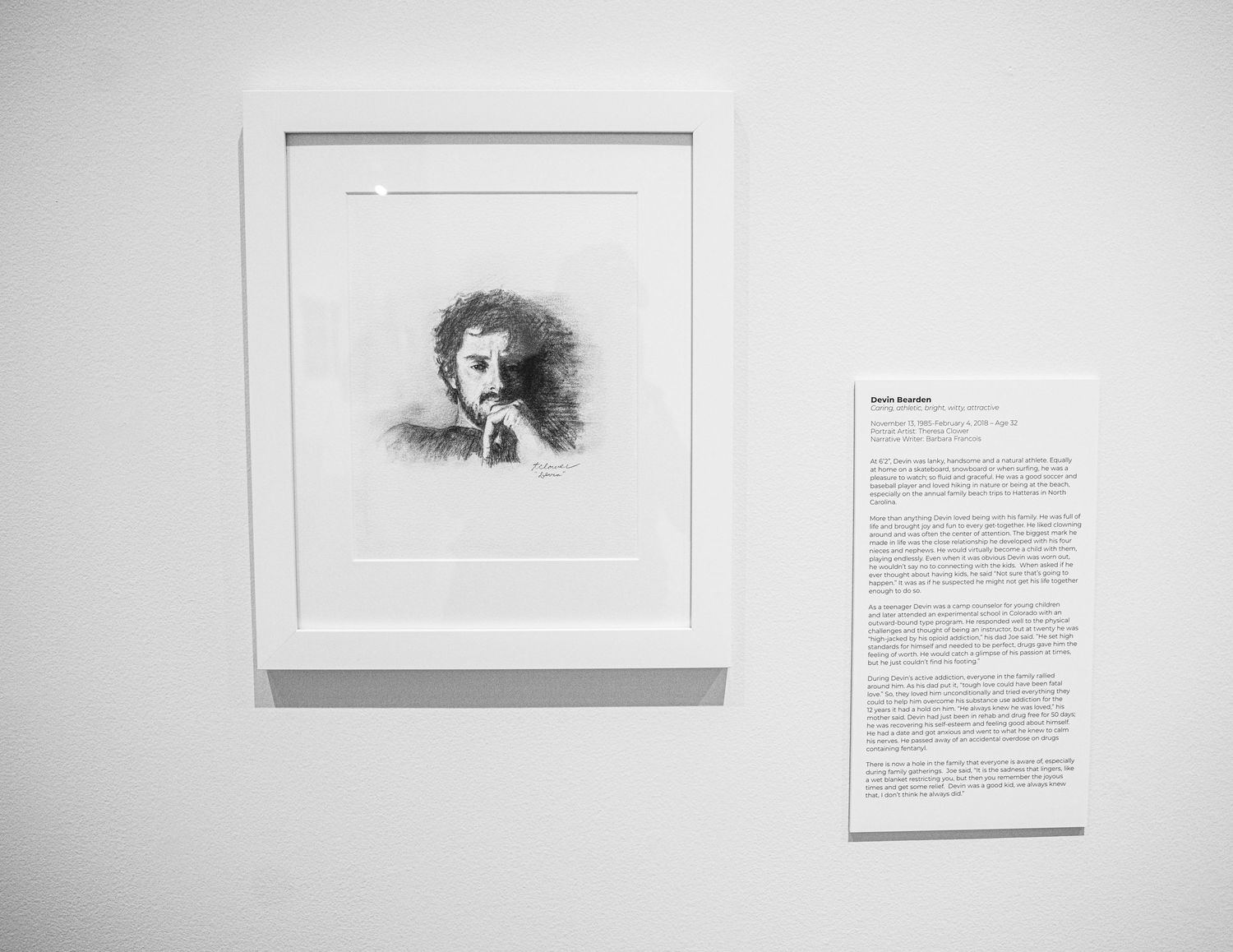 Gallery wall displaying framed artwork and text descriptions in a minimalist white space.