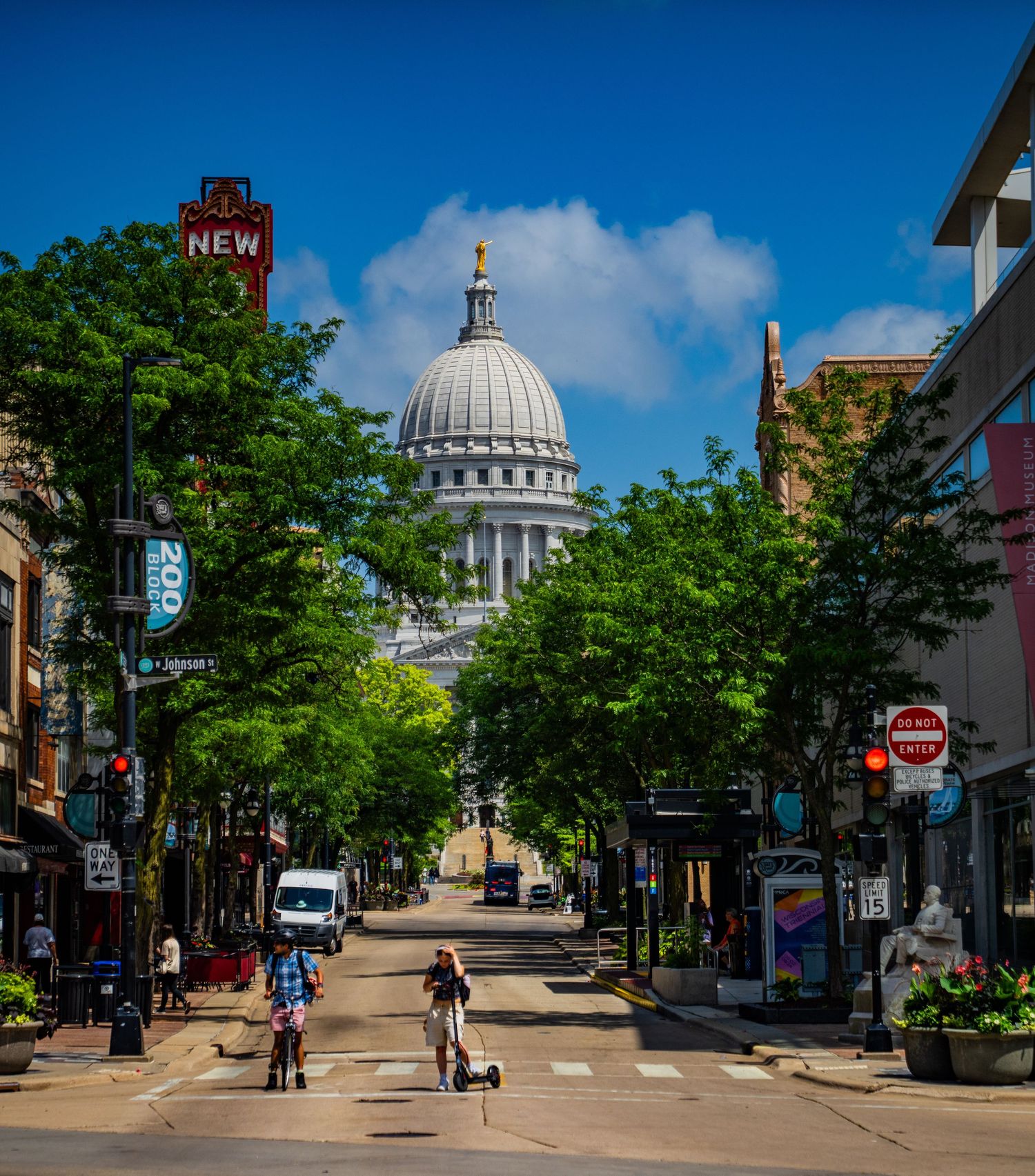 Tree-lined State Street leading to the Wisconsin State Capitol dome under a blue sky in Madison, WI.
