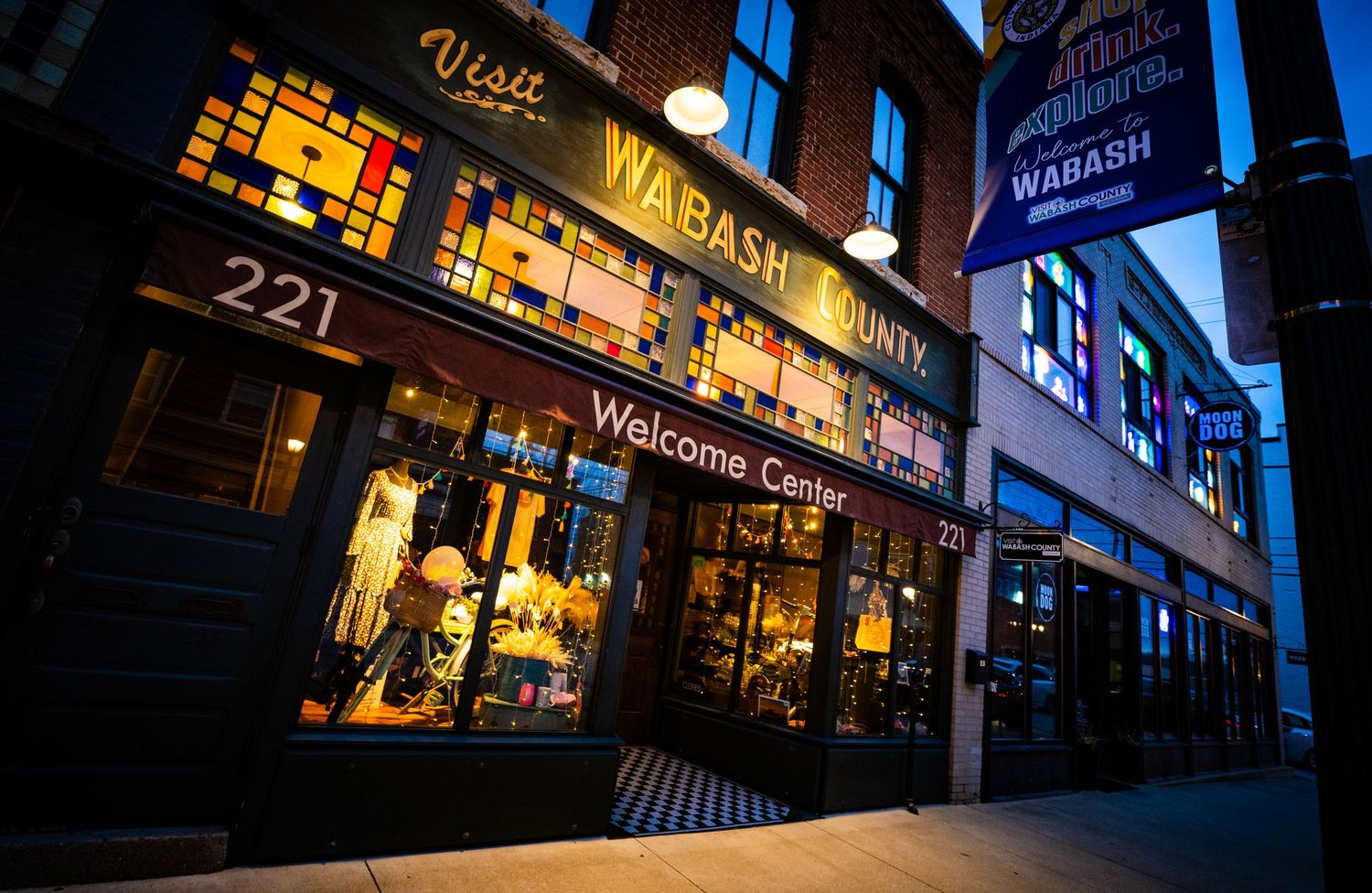 Illuminated storefront of Wabash Antiques shop at night with neon signs.