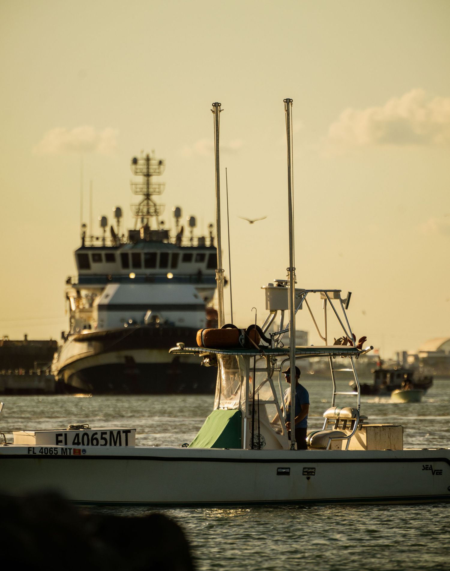 Three fishing boats moored in calm waters during golden hour with warm sunset lighting.