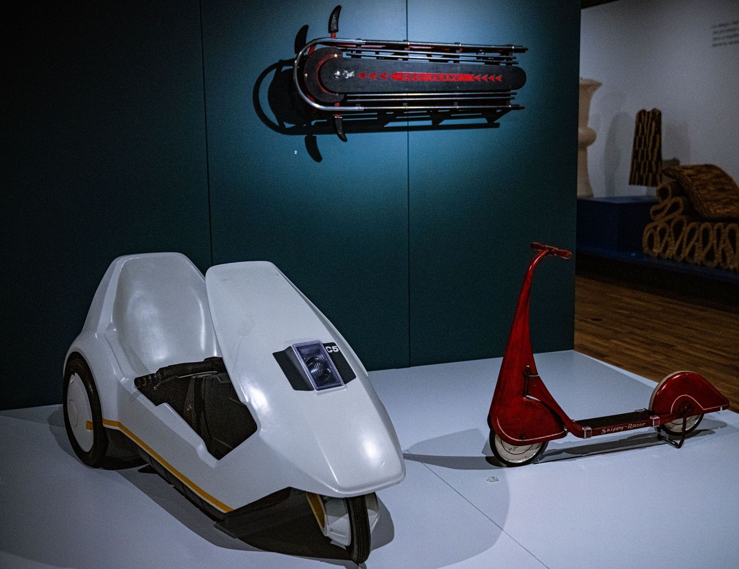 A collection of vintage sleds displayed in a museum setting with dramatic lighting and dark backgrounds.