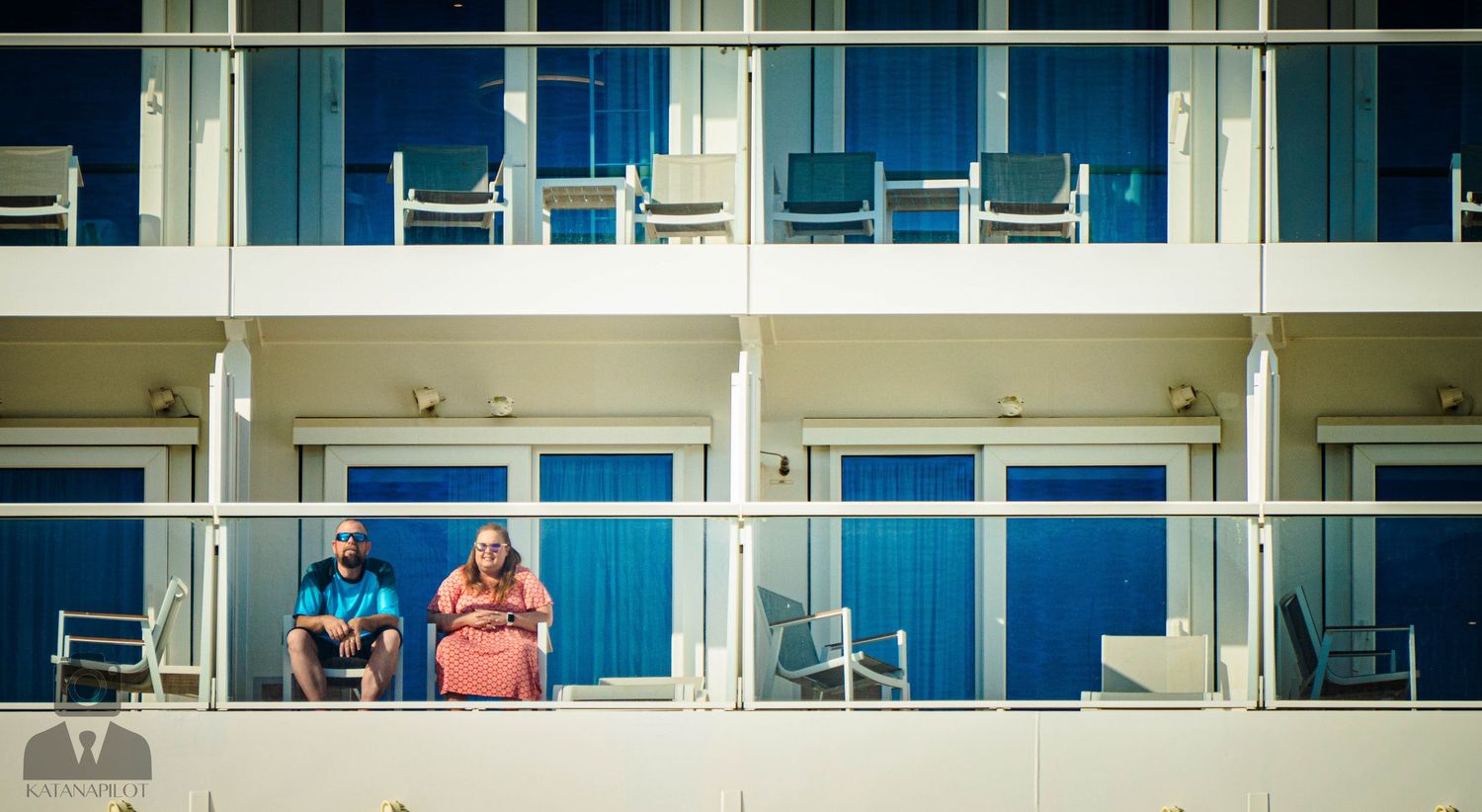 Panoramic view of residential balconies with glass railings on a modern building facade.
