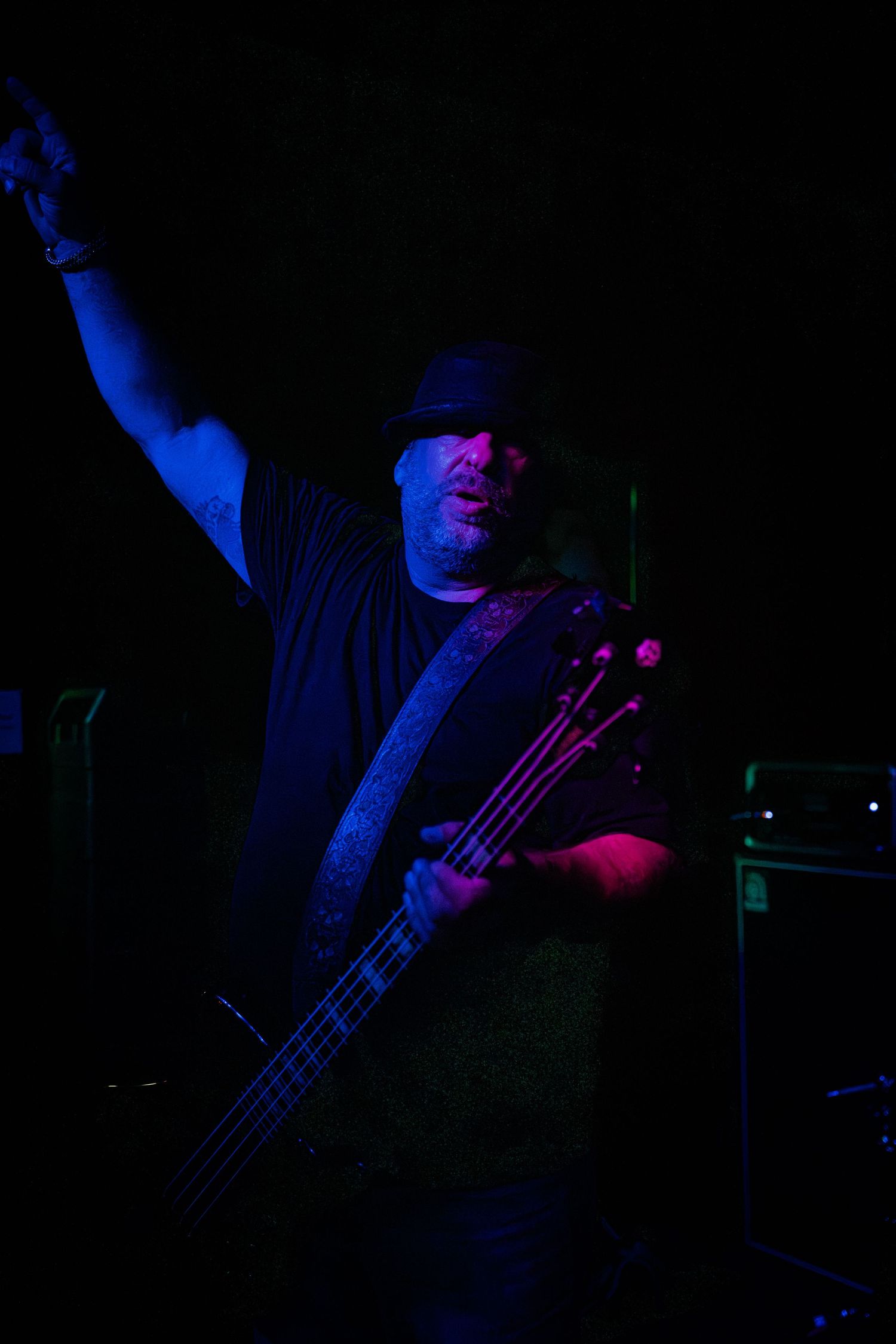 Musician playing bass guitar under blue stage lighting during a live performance.