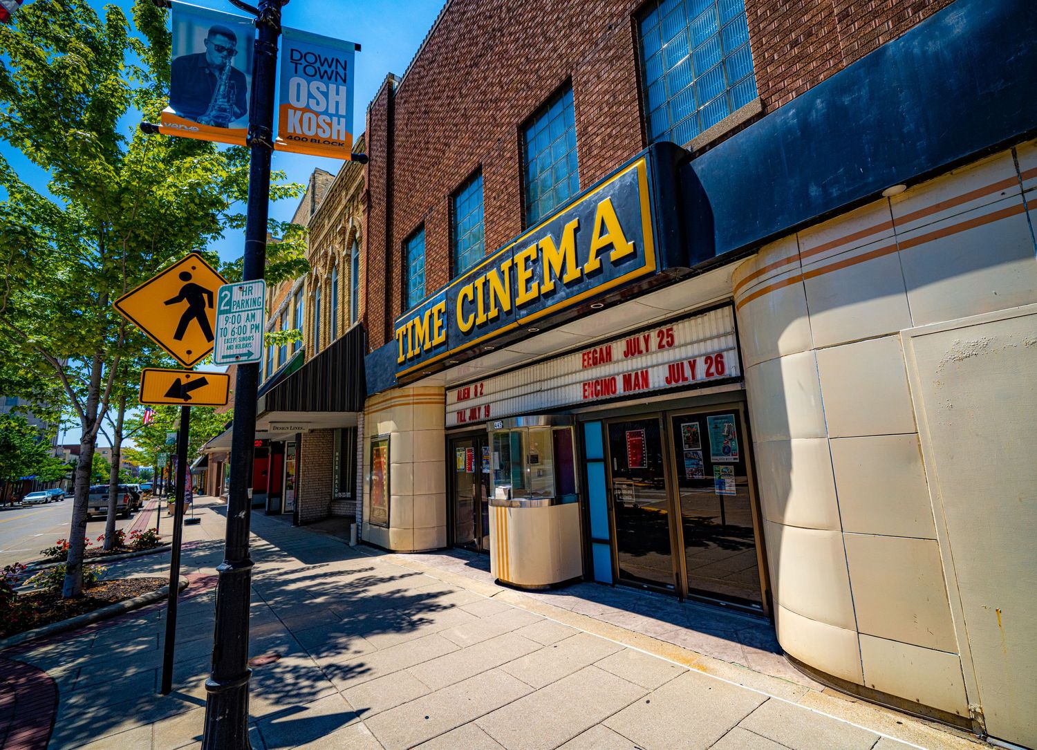 Time Cinema theater entrance with blue awning on a brick building facade in downtown Oshkosh.