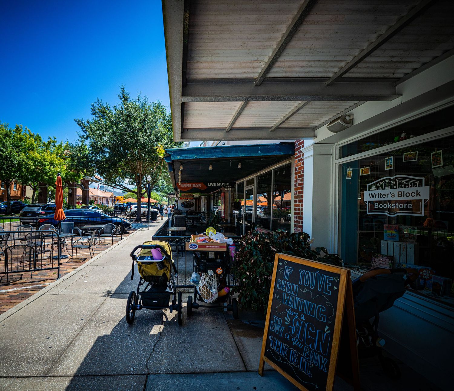 Covered outdoor marketplace with shops and pedestrian walkways under blue sky.
