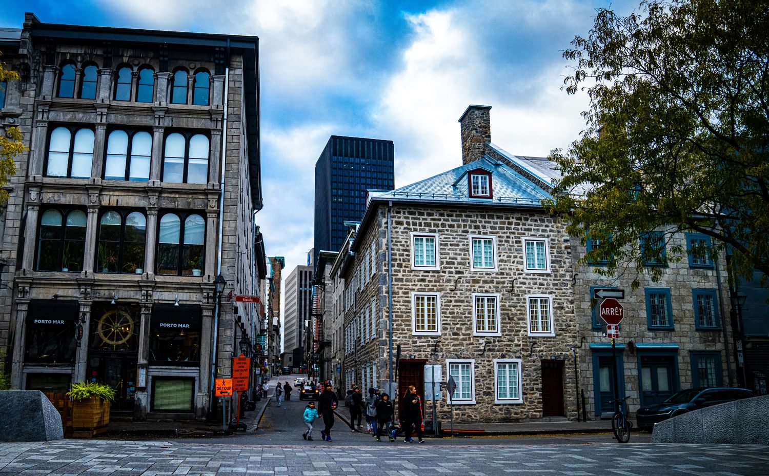 Historic stone buildings line a cobblestone street in Old Quebec City's charming historic district on a sunny day.