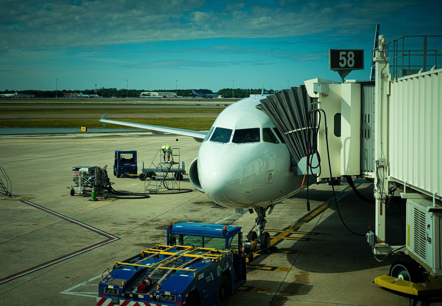 Commercial aircraft parked at airport gates with passenger boarding bridges and ground service equipment.