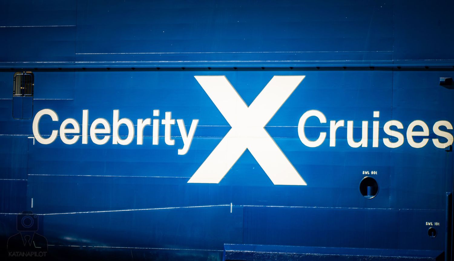 A glowing blue Celebrity Cruises logo illuminated against a dark background.