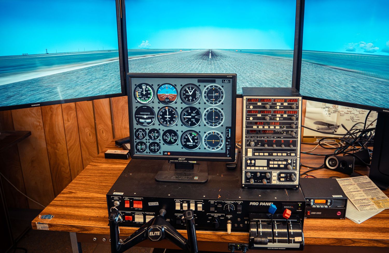 Wide view of flight simulator screens showing runway approach and instrument readouts.