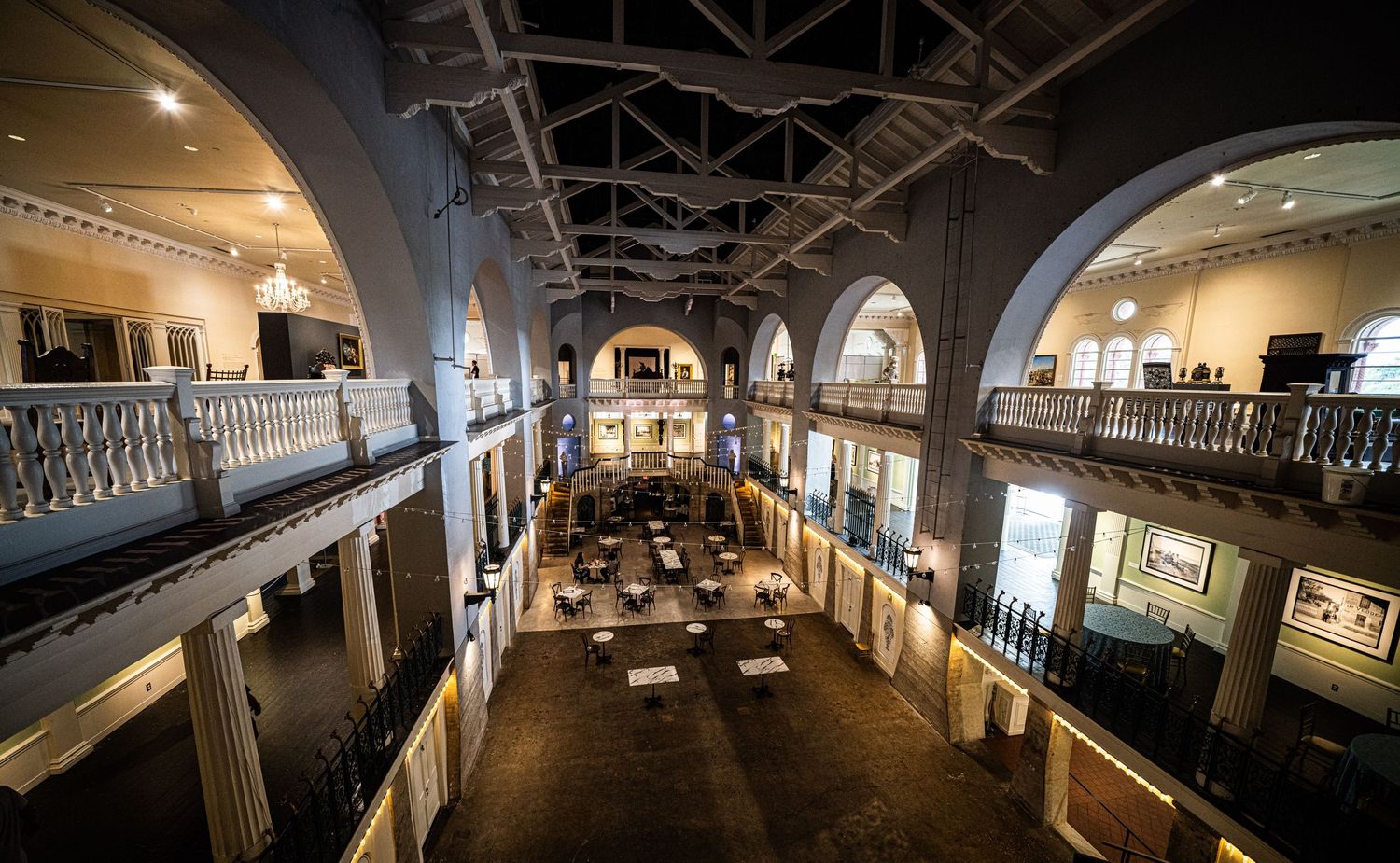 Museum gallery interior with arched ceiling and balcony overlooking exhibition space.