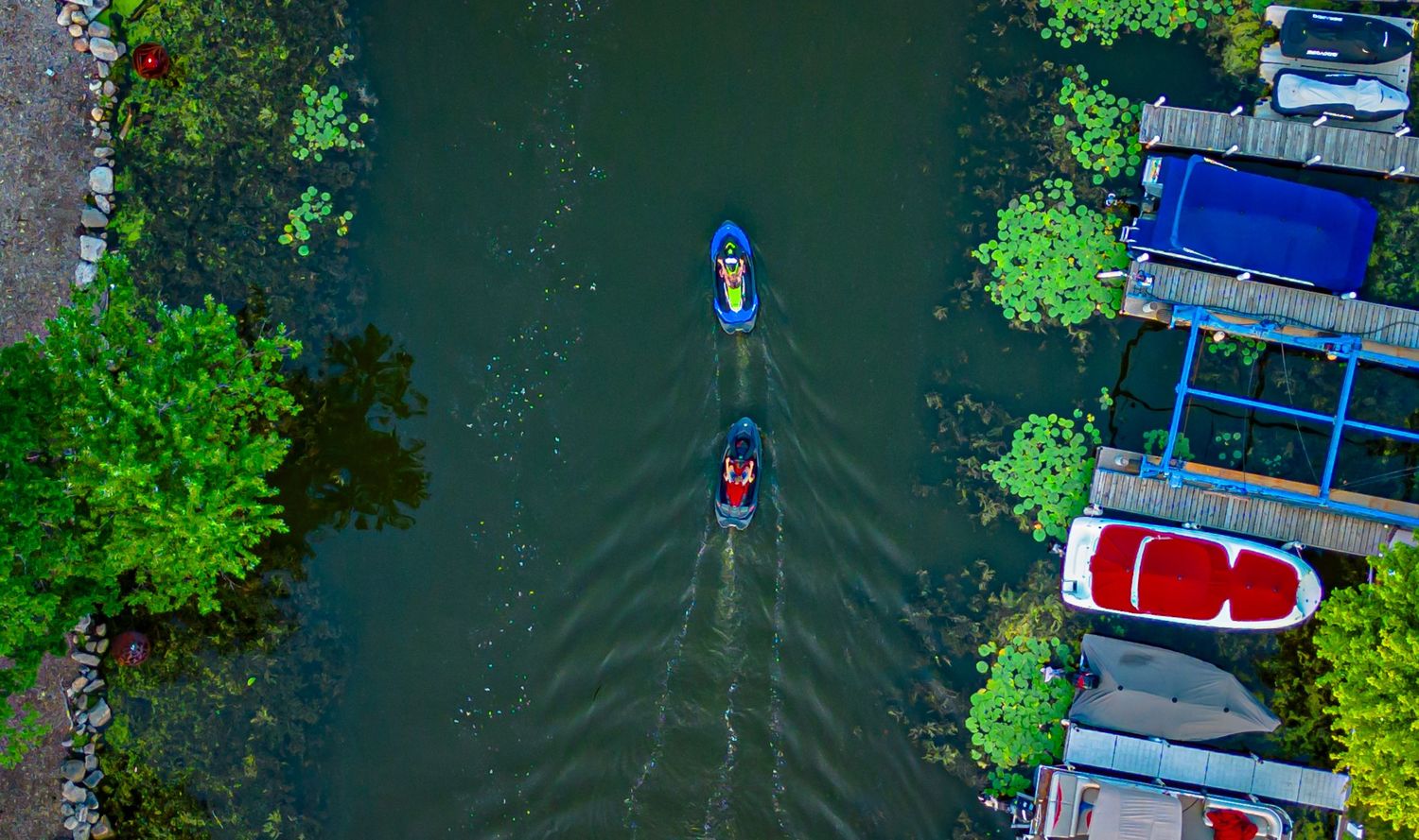 Boats and docks line a marina waterway surrounded by lush green trees.