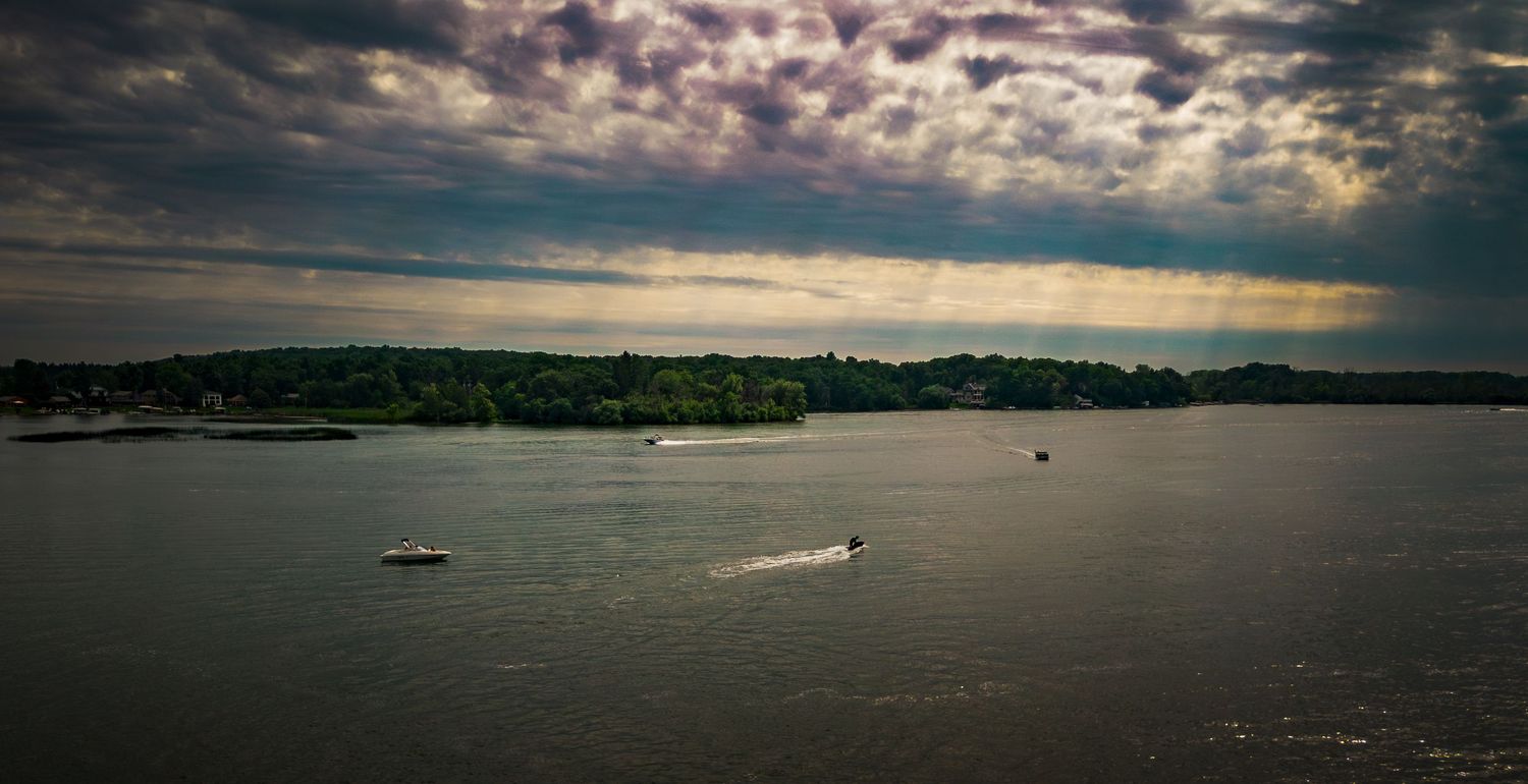 Wide landscape shot of a waterfront with moody clouds and distant shoreline.