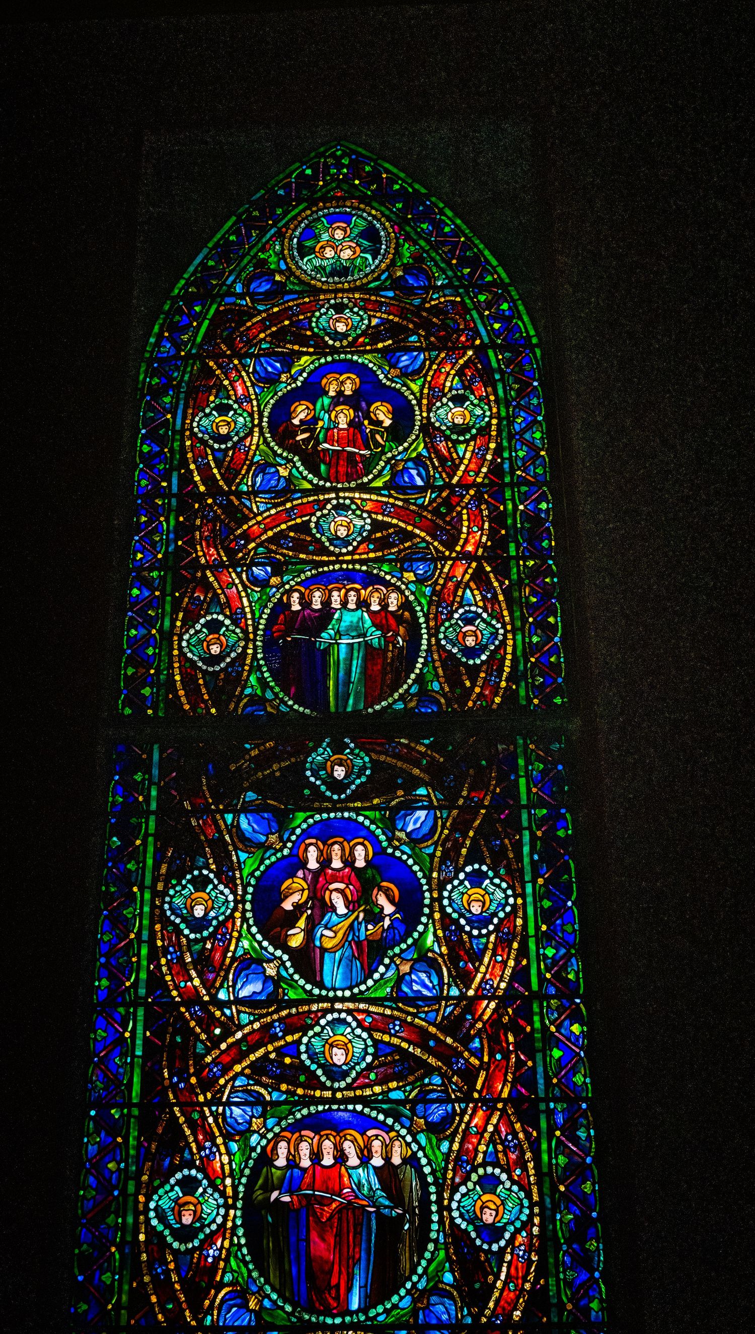 Gothic-style stained glass window with intricate medallions and ornate religious imagery in jewel tones.