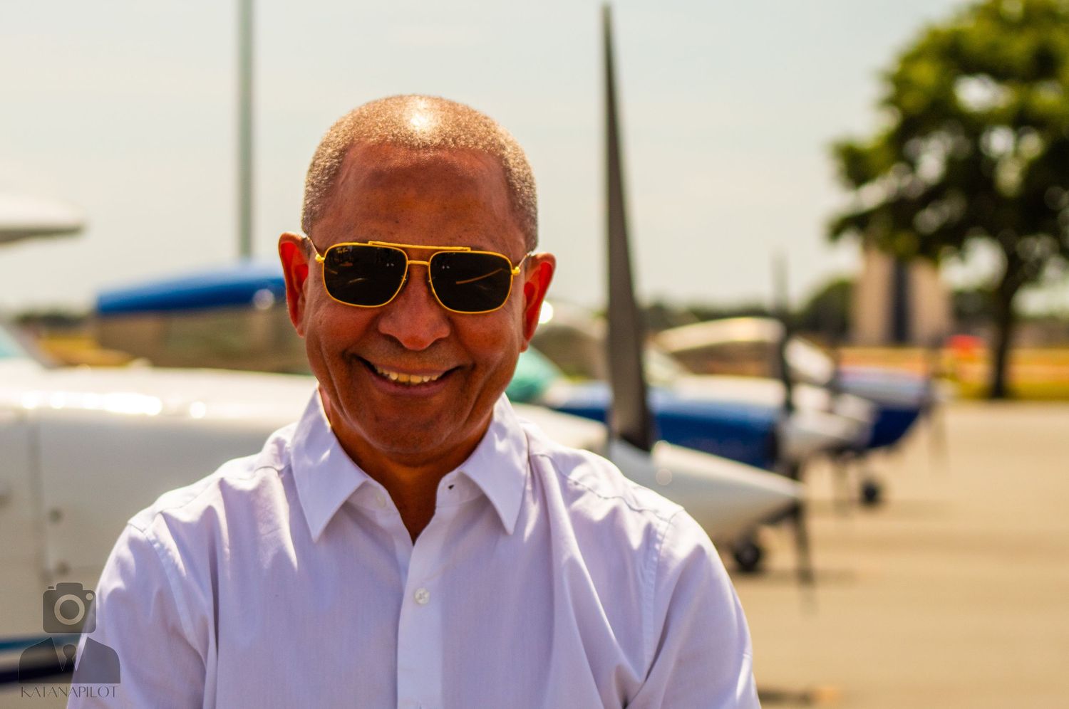Professional aviation staff members wearing white shirts and sunglasses pose outdoors near aircraft.