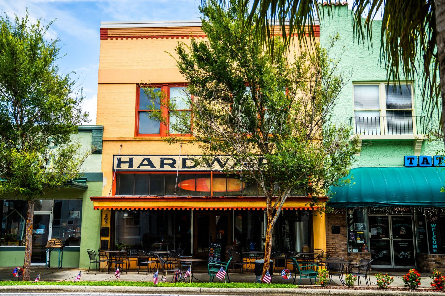Row of colorful modern commercial storefronts with mint green and orange facades along a street.