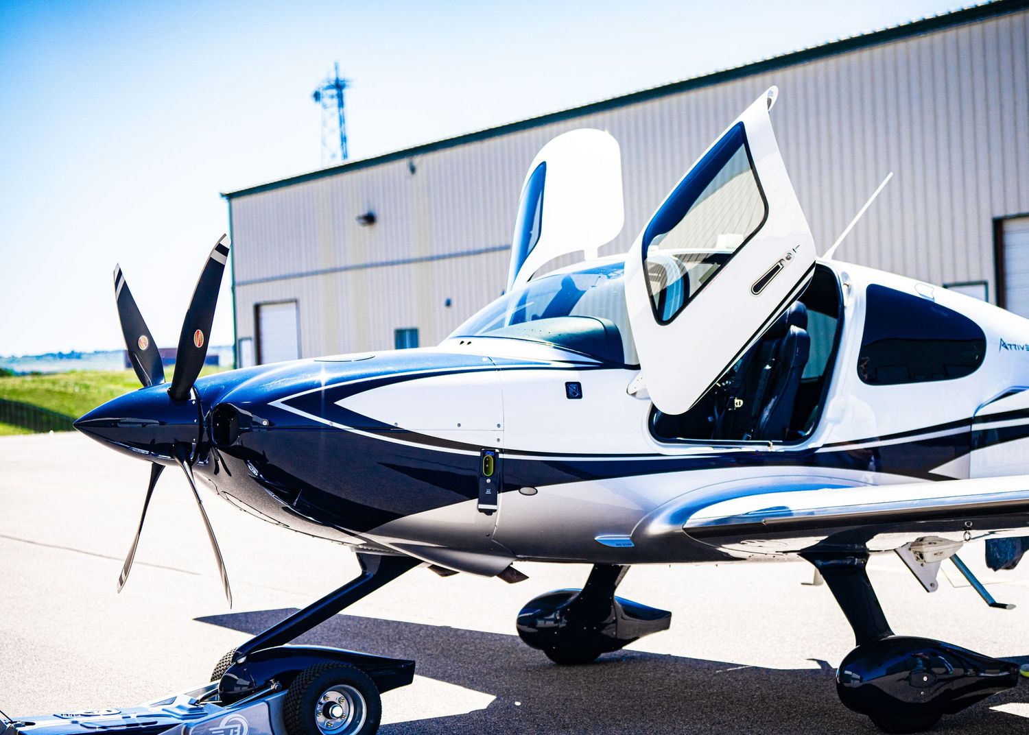 Multiple views of parked aircraft outside metal hangars on sunny day.