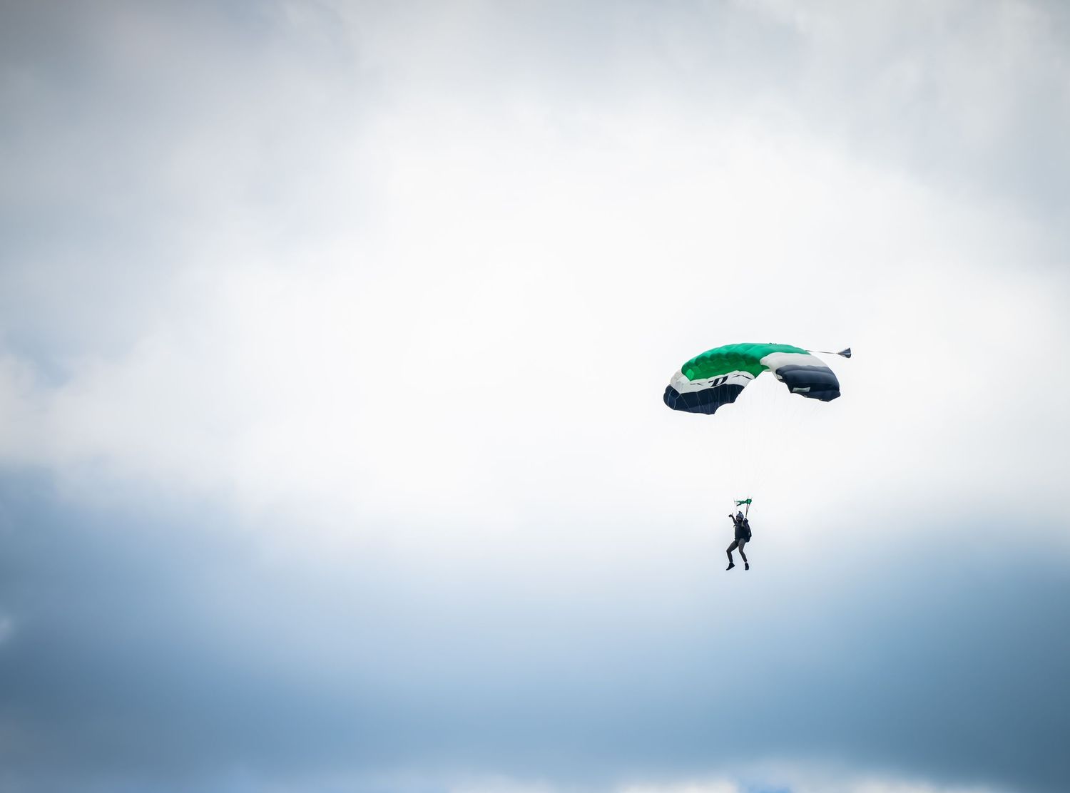 Aerial view of parachute landing sequence against cloudy sky.