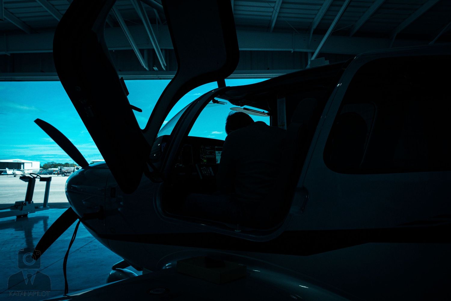 Silhouettes of military aircraft and drones in a dark hangar with dramatic lighting.