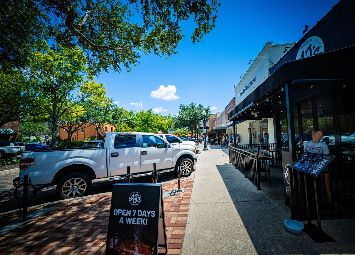Street view of urban storefronts with brick details and pedestrian walkway.