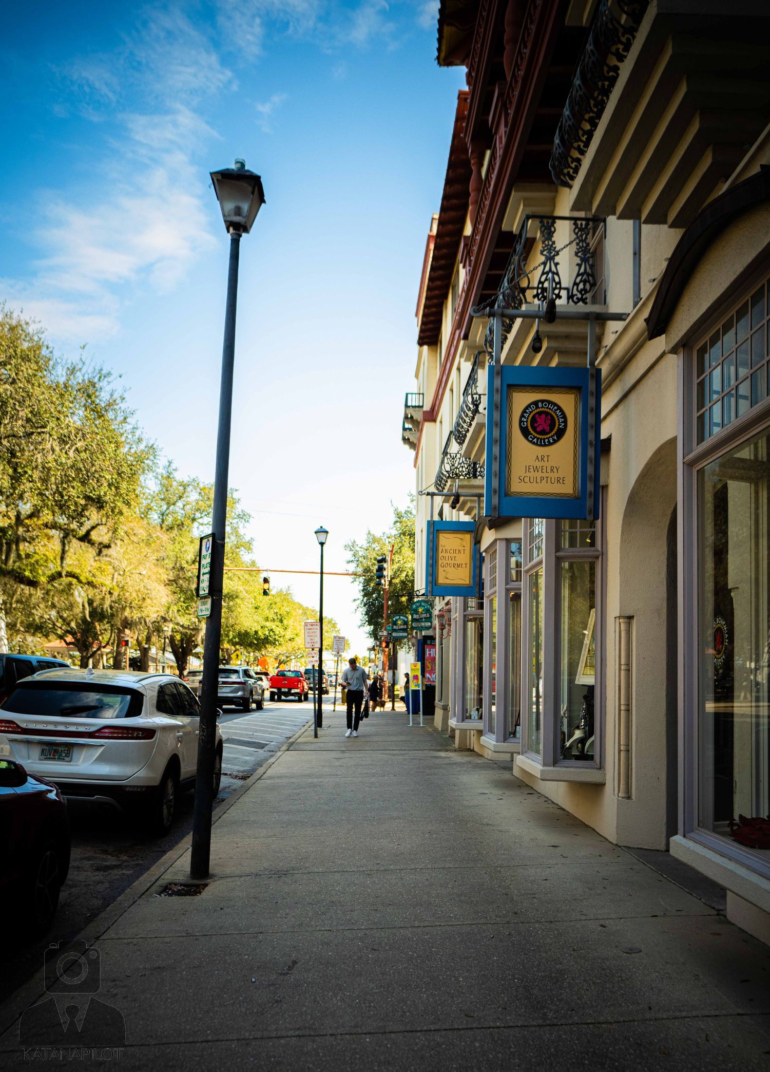 Empty sidewalk with storefronts and lamp posts along historic downtown street.