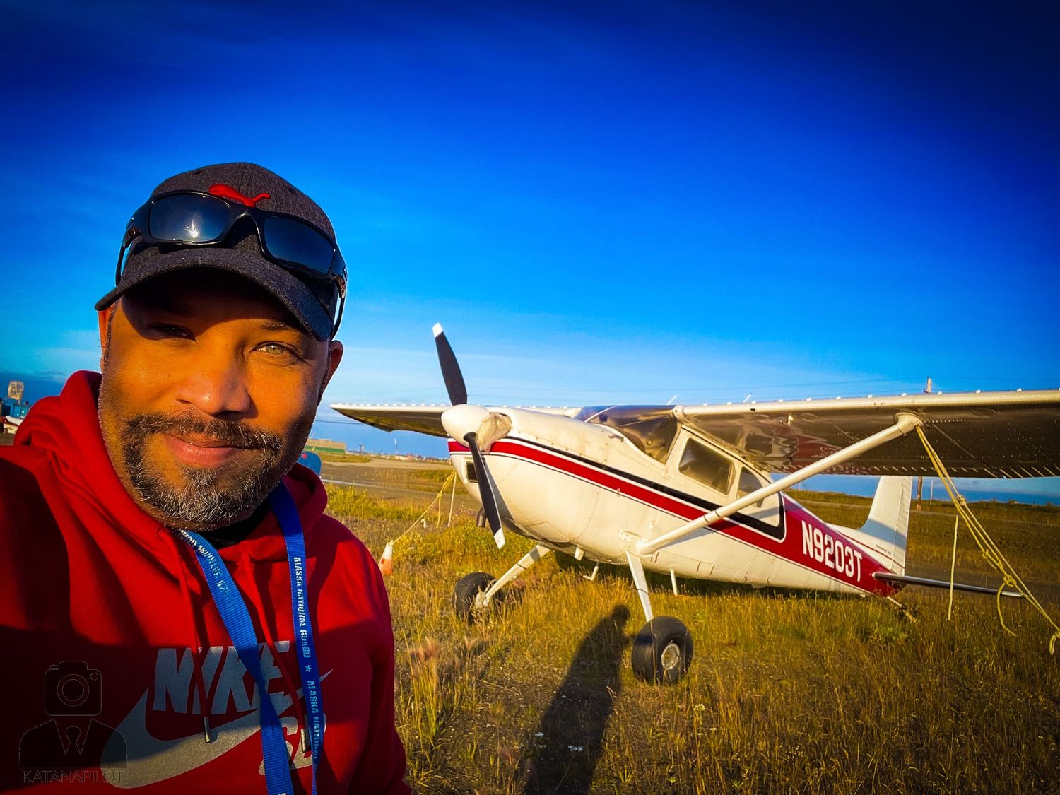 Small private aircraft parked on grass airfield during golden hour.
