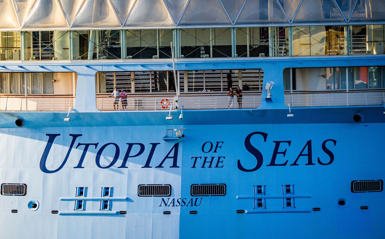 Royal Caribbean's Utopia of the Seas cruise ship docked in Nassau, with passengers visible on the deck.
