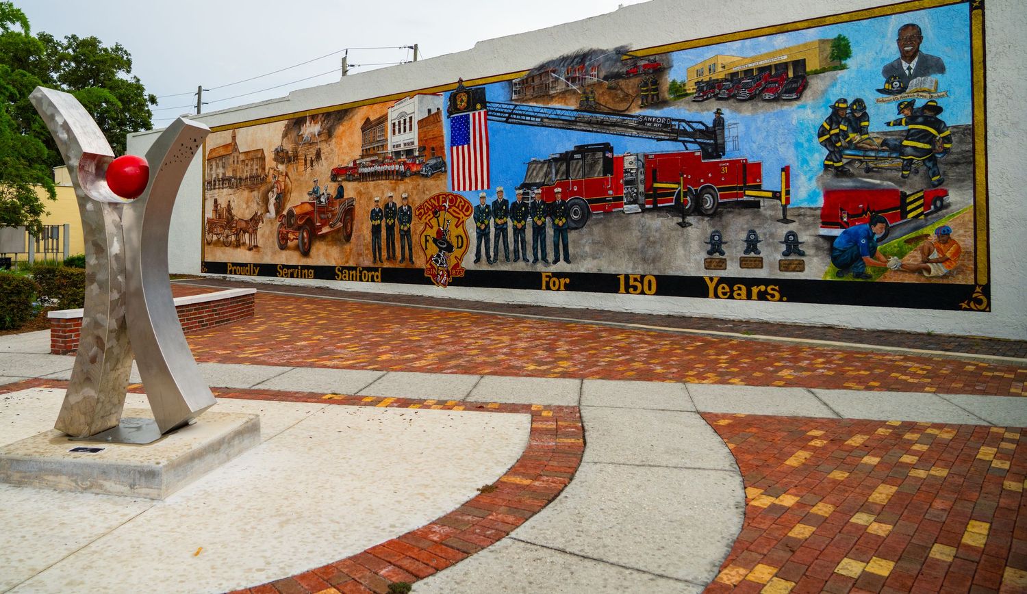 Colorful wall murals depicting local history and culture along a downtown walkway.