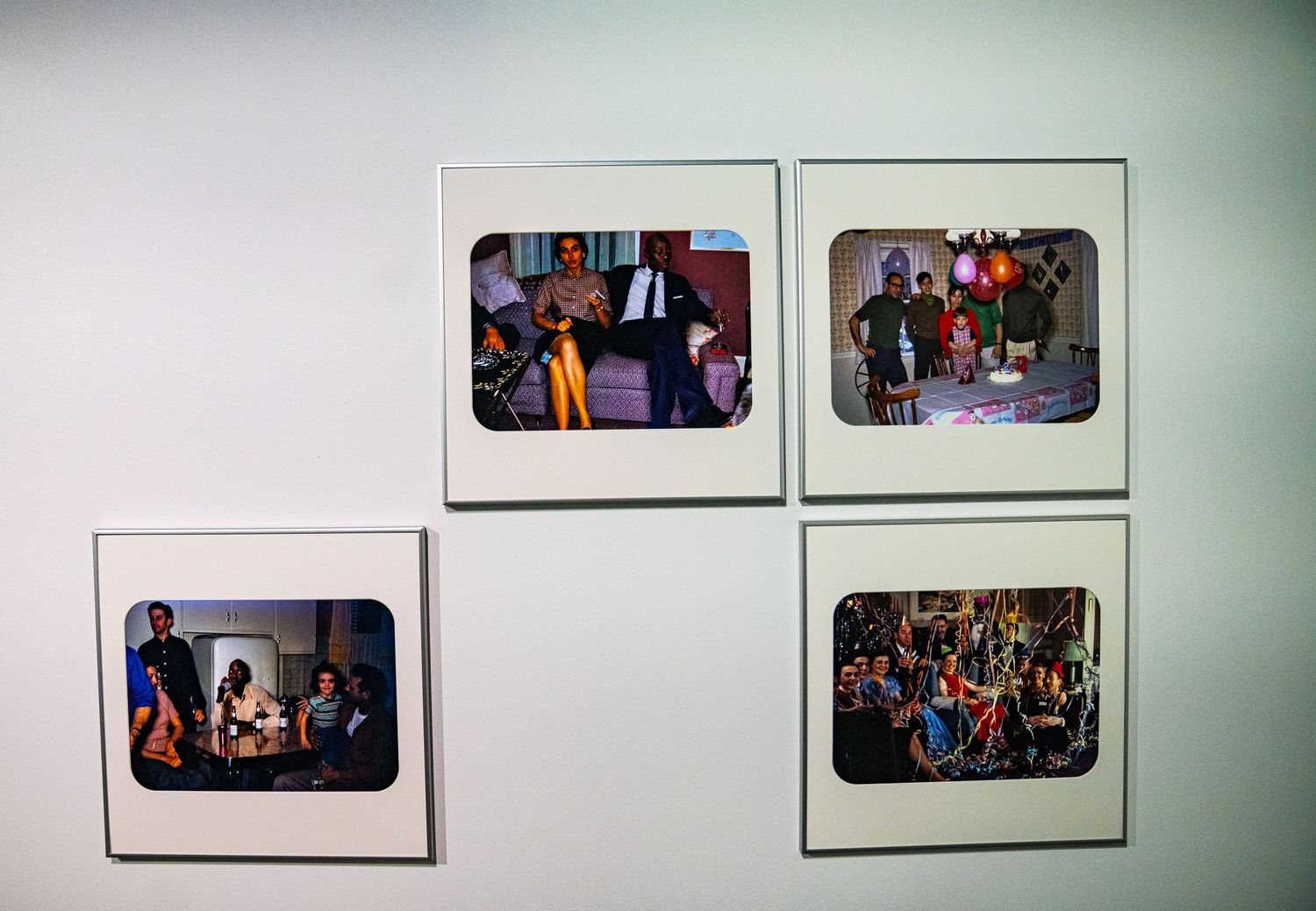 Exhibition space showing a collection of mounted photographs against a white wall.
