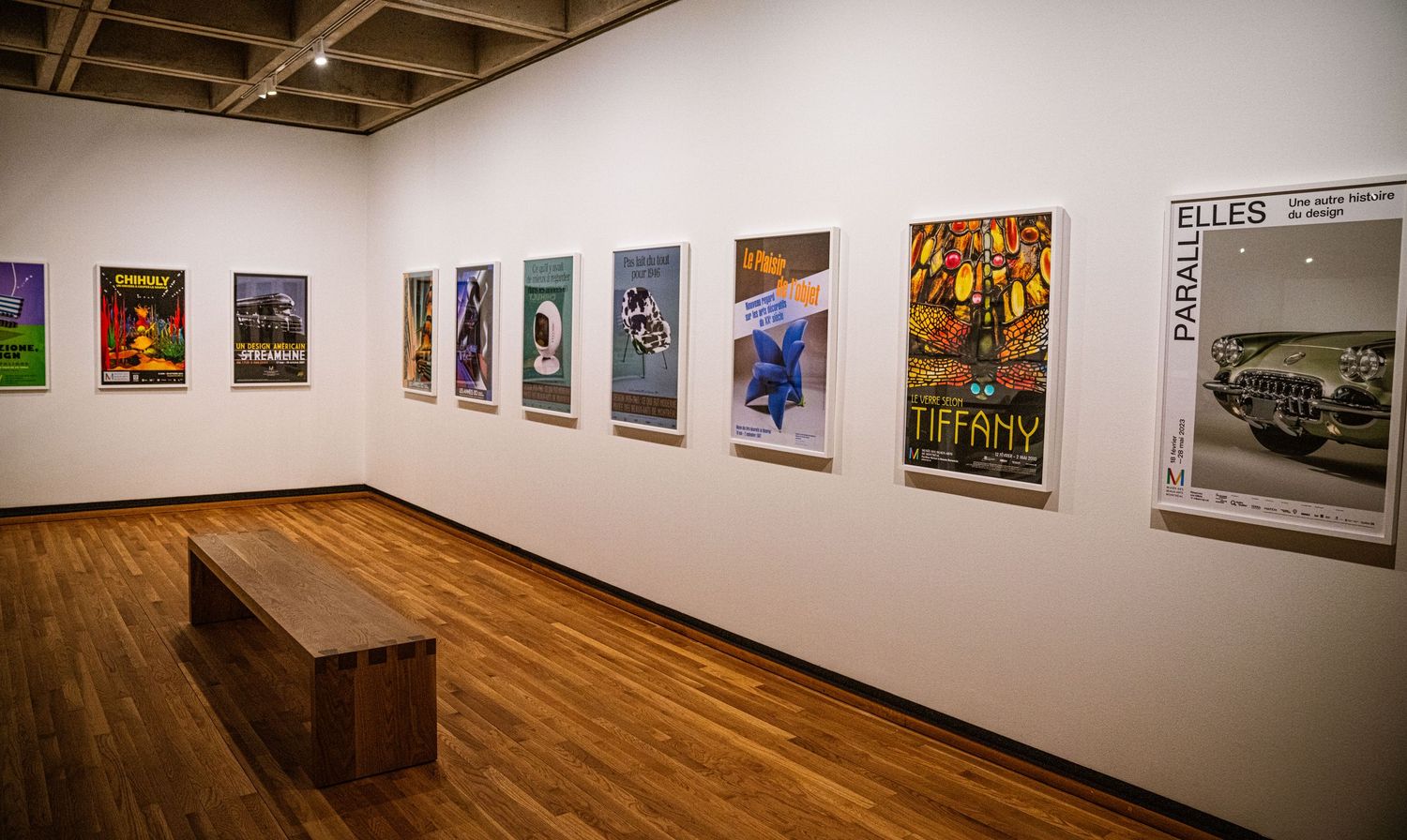 Art gallery interior with hardwood floors and white walls displaying framed photographs in a panoramic view.