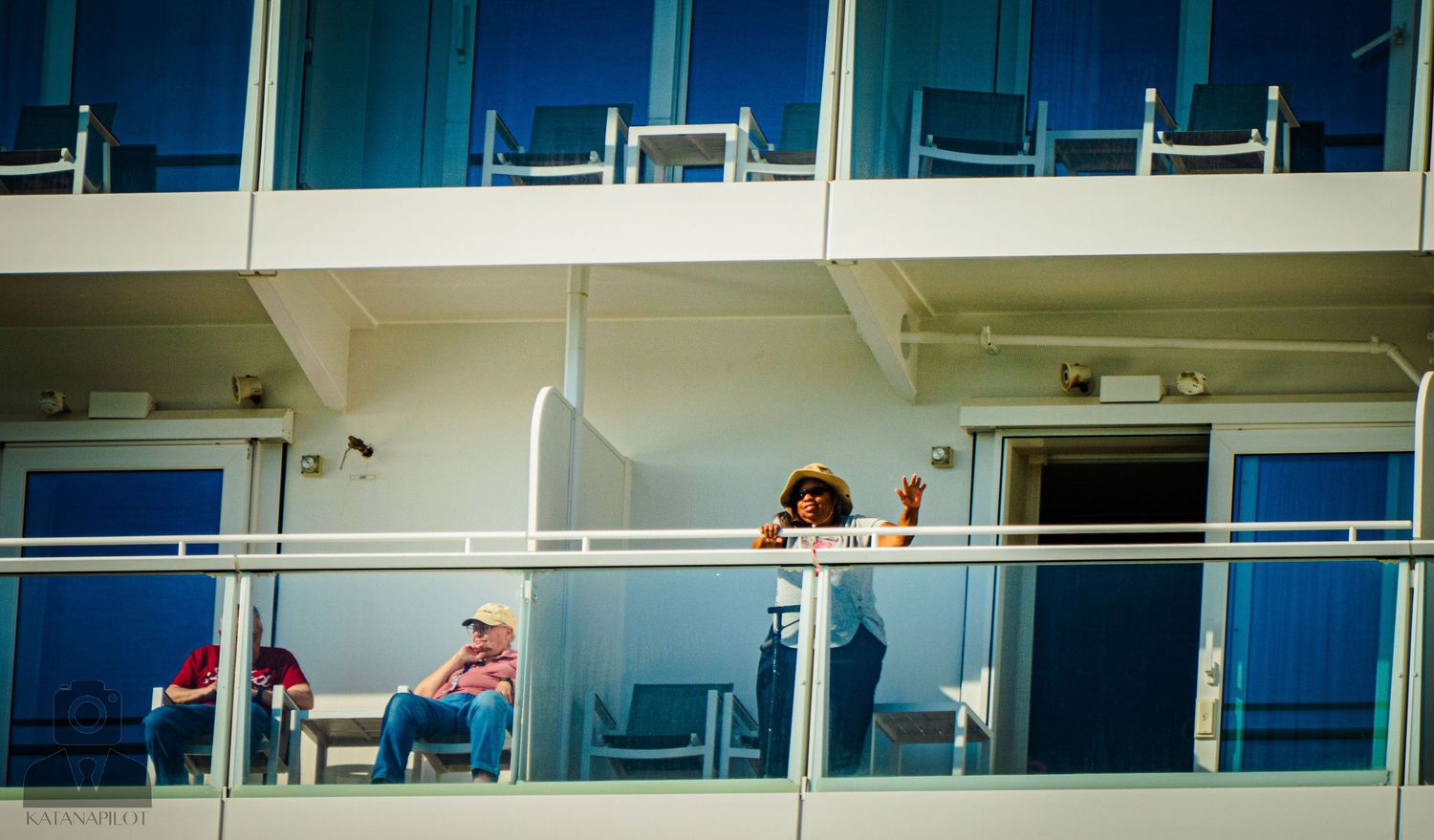People enjoying the view from blue and white balconies on a cruise ship deck.