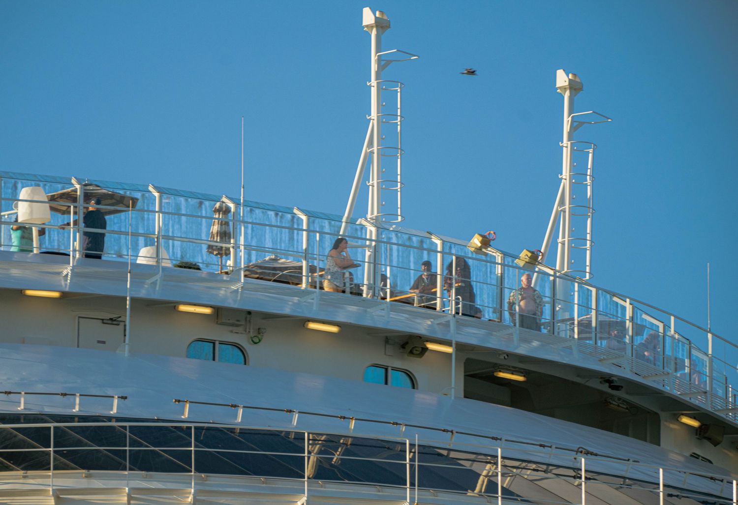 A white cruise ship deck with railings and safety equipment shown in a series of connected photos against a blue sky.