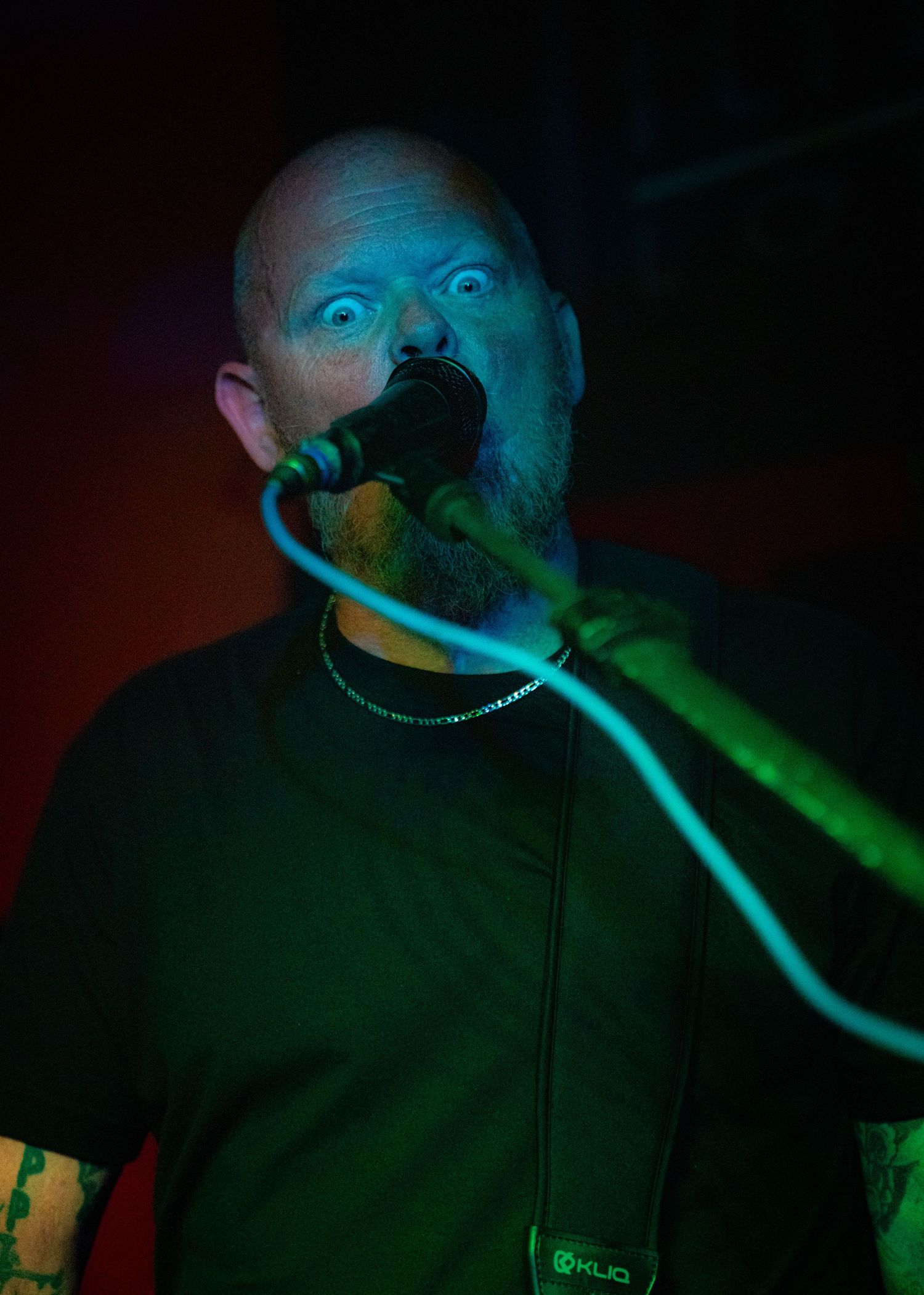 Performer in black clothing illuminated by striking green stage lights during a show.