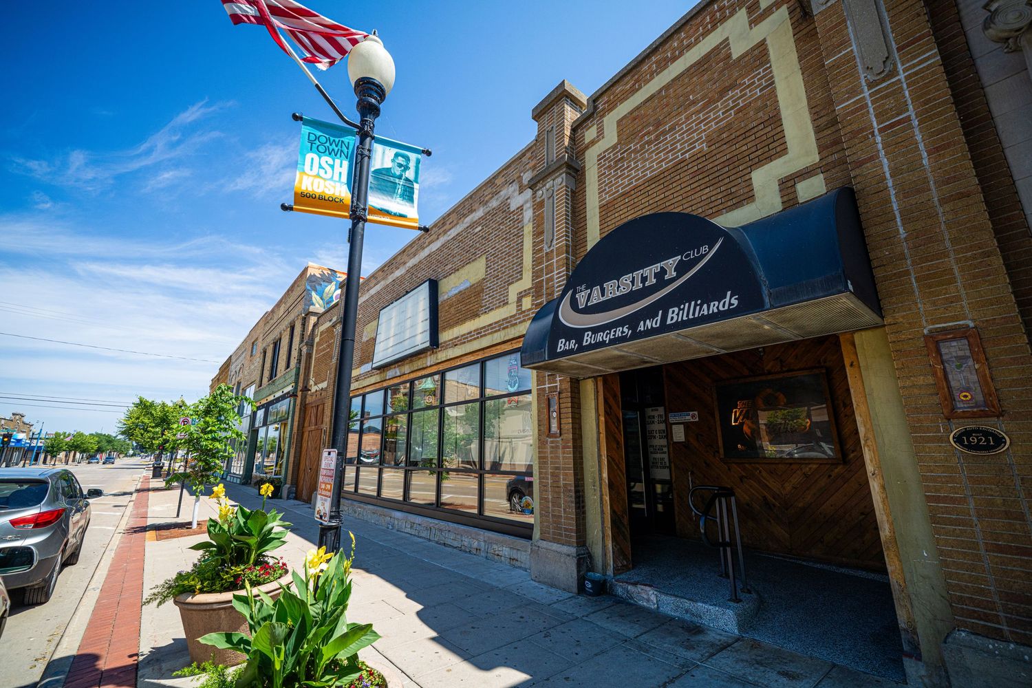 Street view of brick buildings with British and Irish flags flying above storefronts.