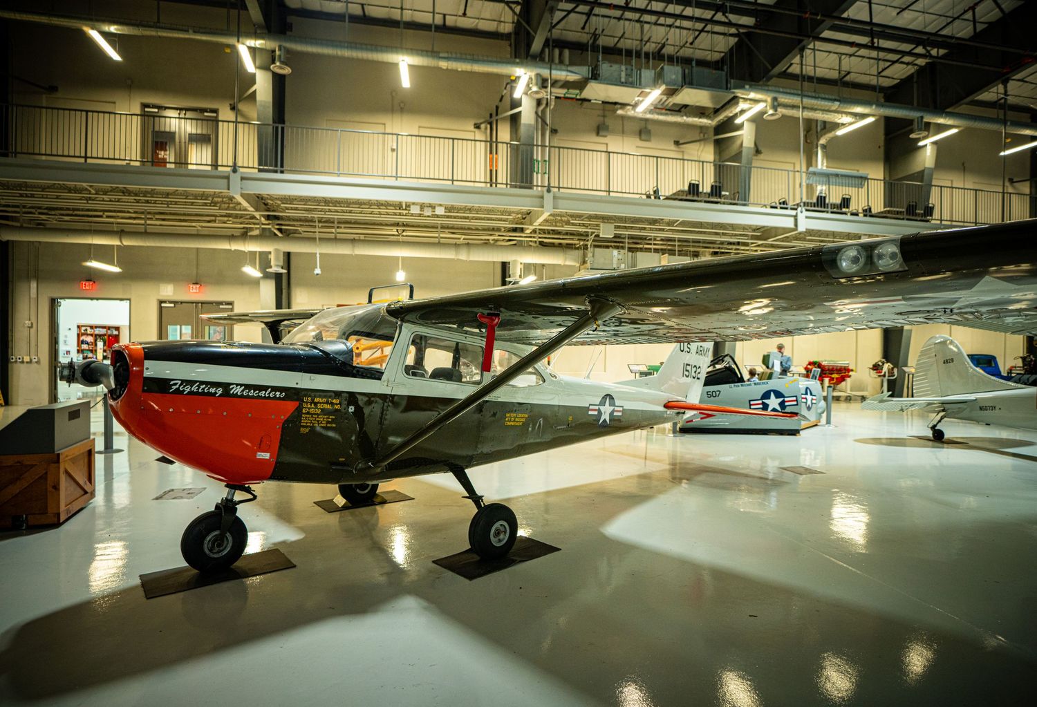 Classic red and black small aircraft on display inside a spacious aviation museum hangar.