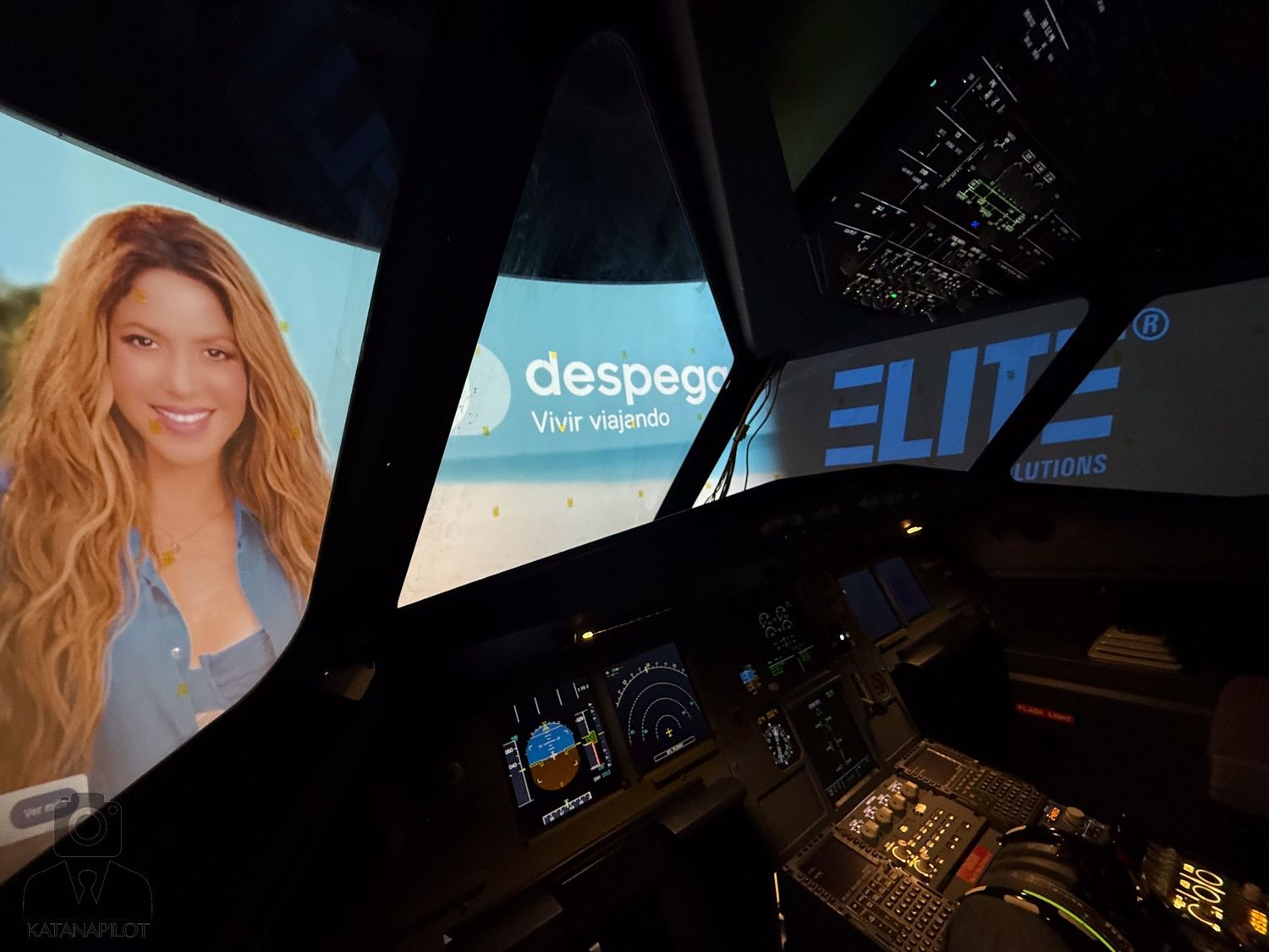 Flight simulator cockpit interior with illuminated displays and controls at night.