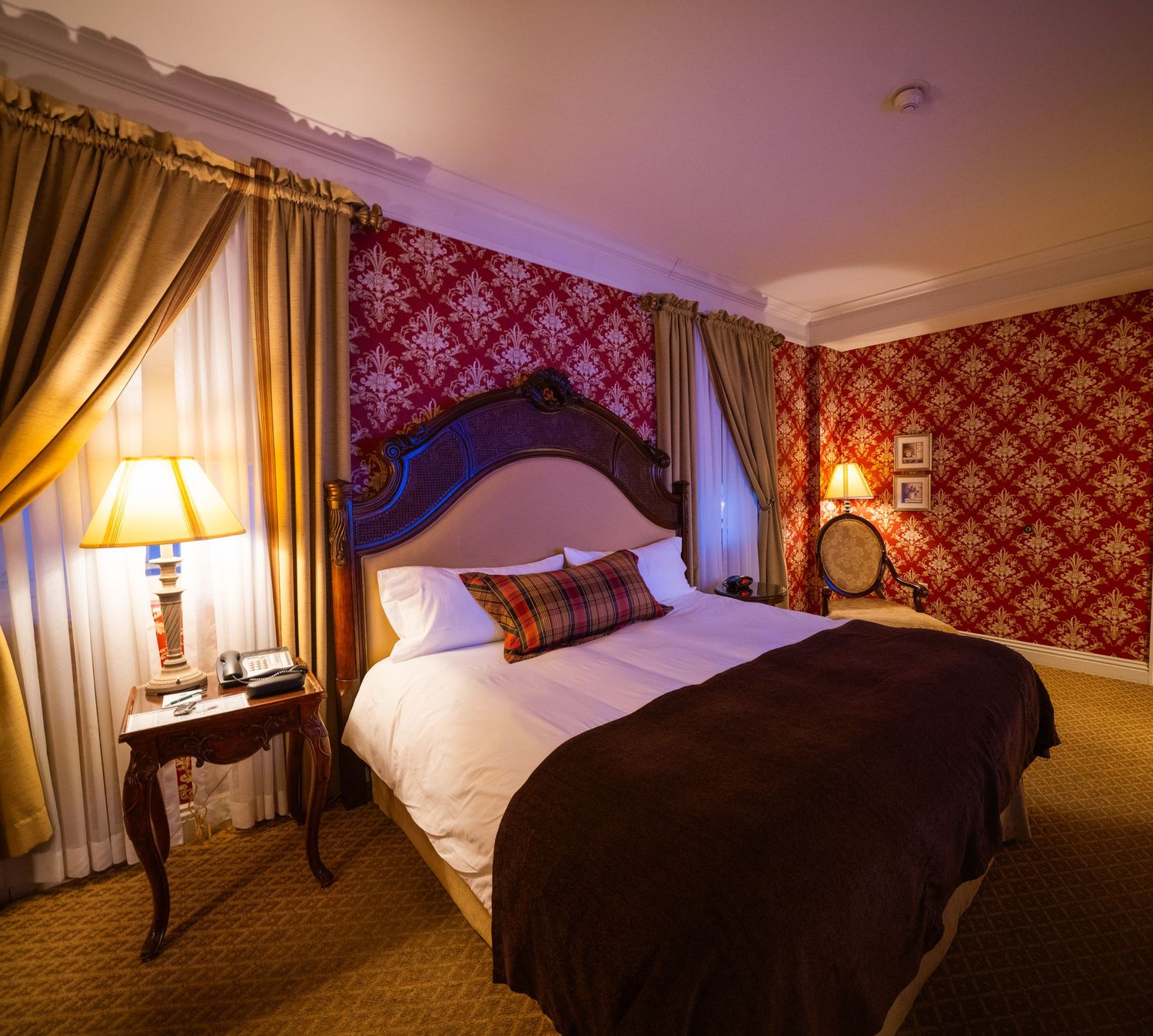 Luxurious hotel room with red damask wallpaper and elegant gold curtains.