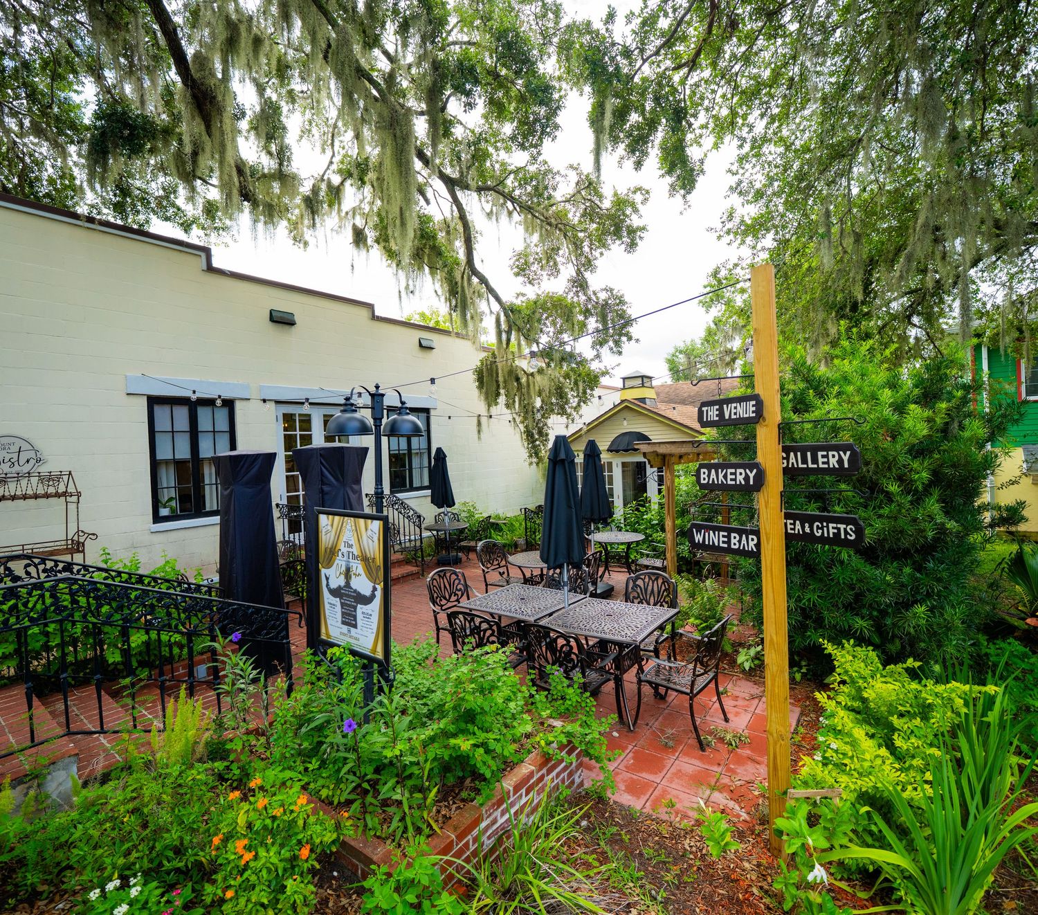 Outdoor patio seating area surrounded by lush tropical plants and garden landscaping.