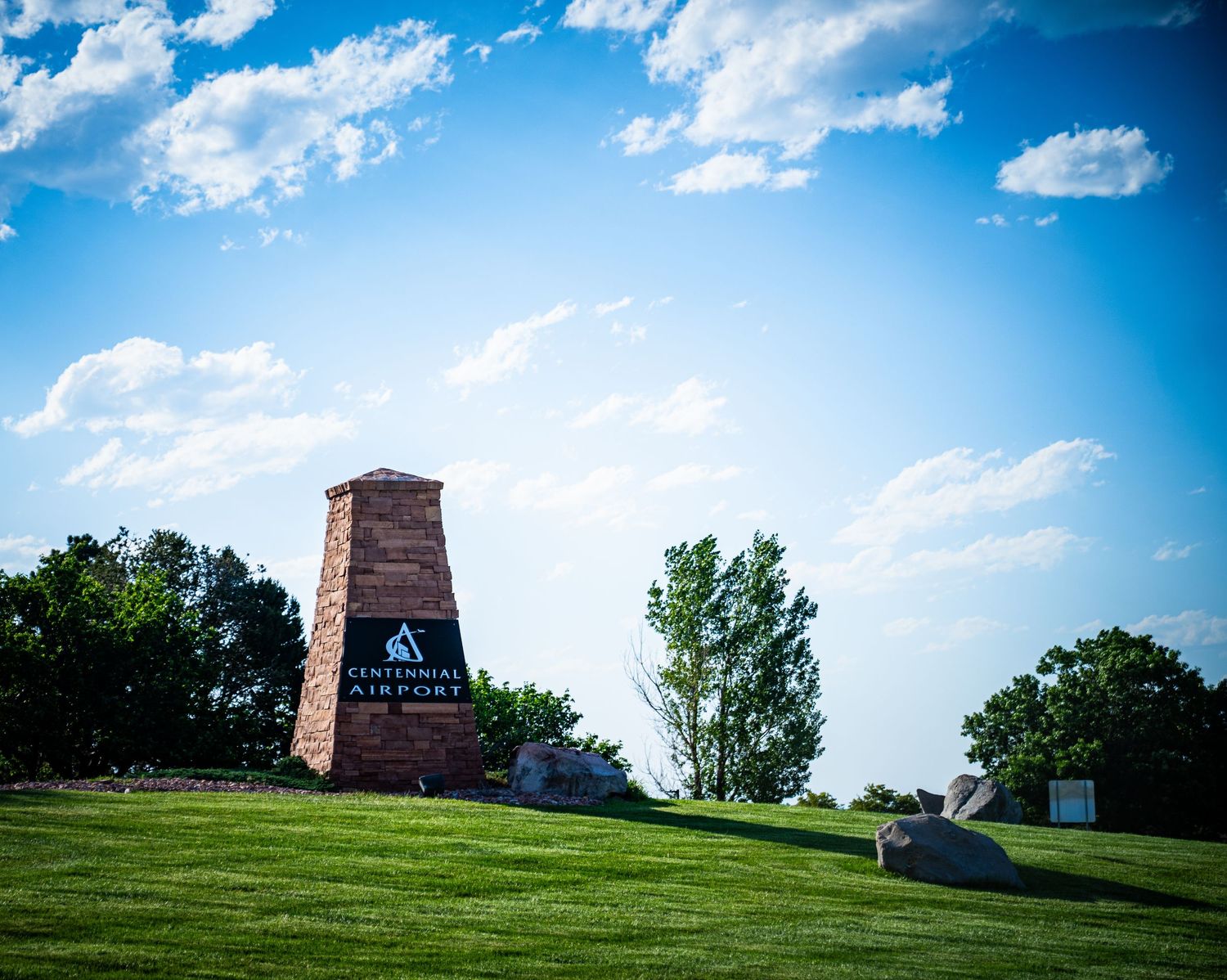 Scenic view of brick monuments on a grassy hillside under blue skies with white puffy clouds.