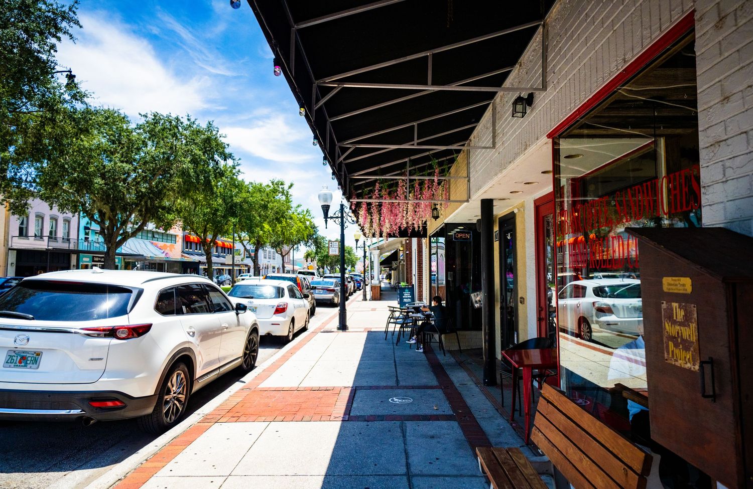 Wide-angle view of covered downtown walkway with parked cars and storefronts.