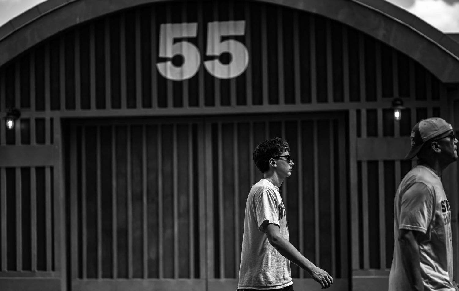 Two people walk past a building with the number 55 displayed prominently in black and white.