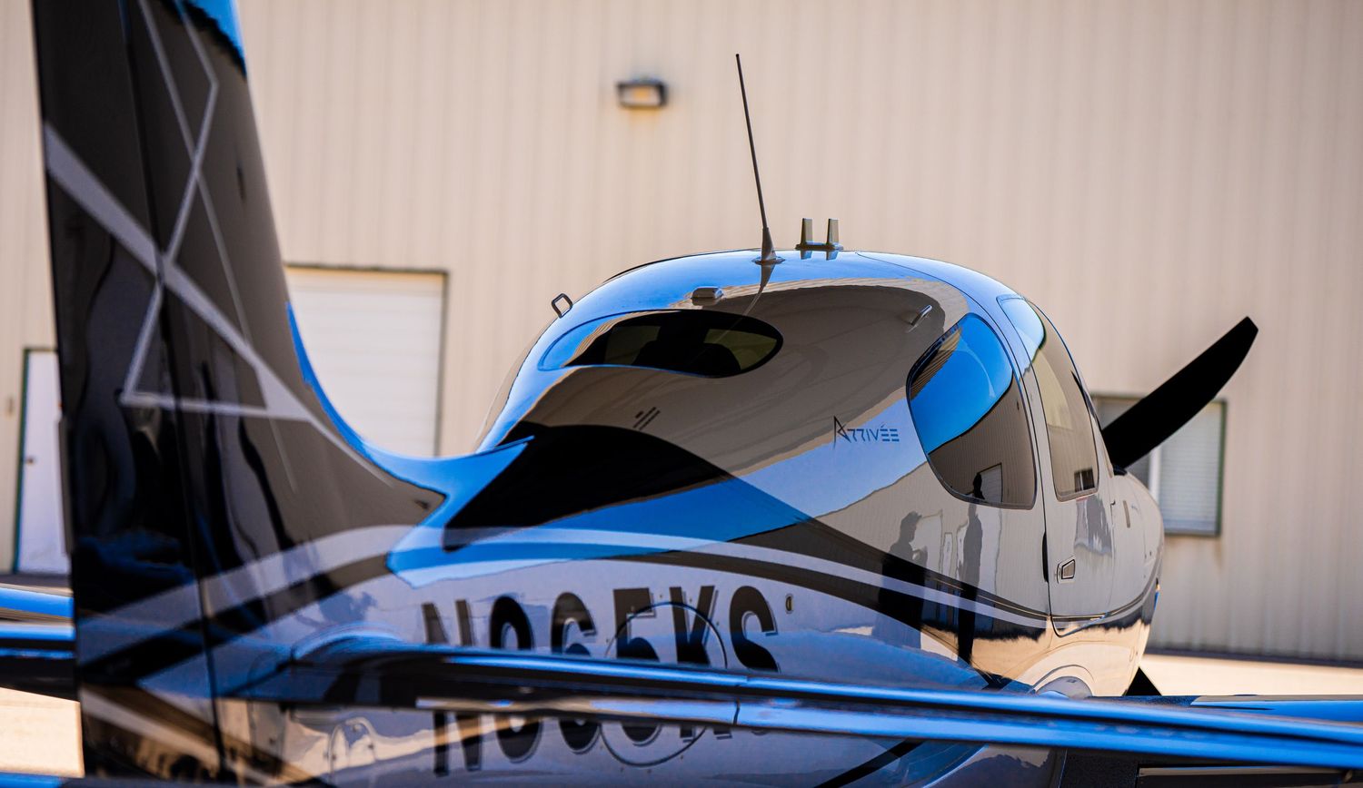Side profile of a sleek blue and white private aircraft in an indoor hangar.